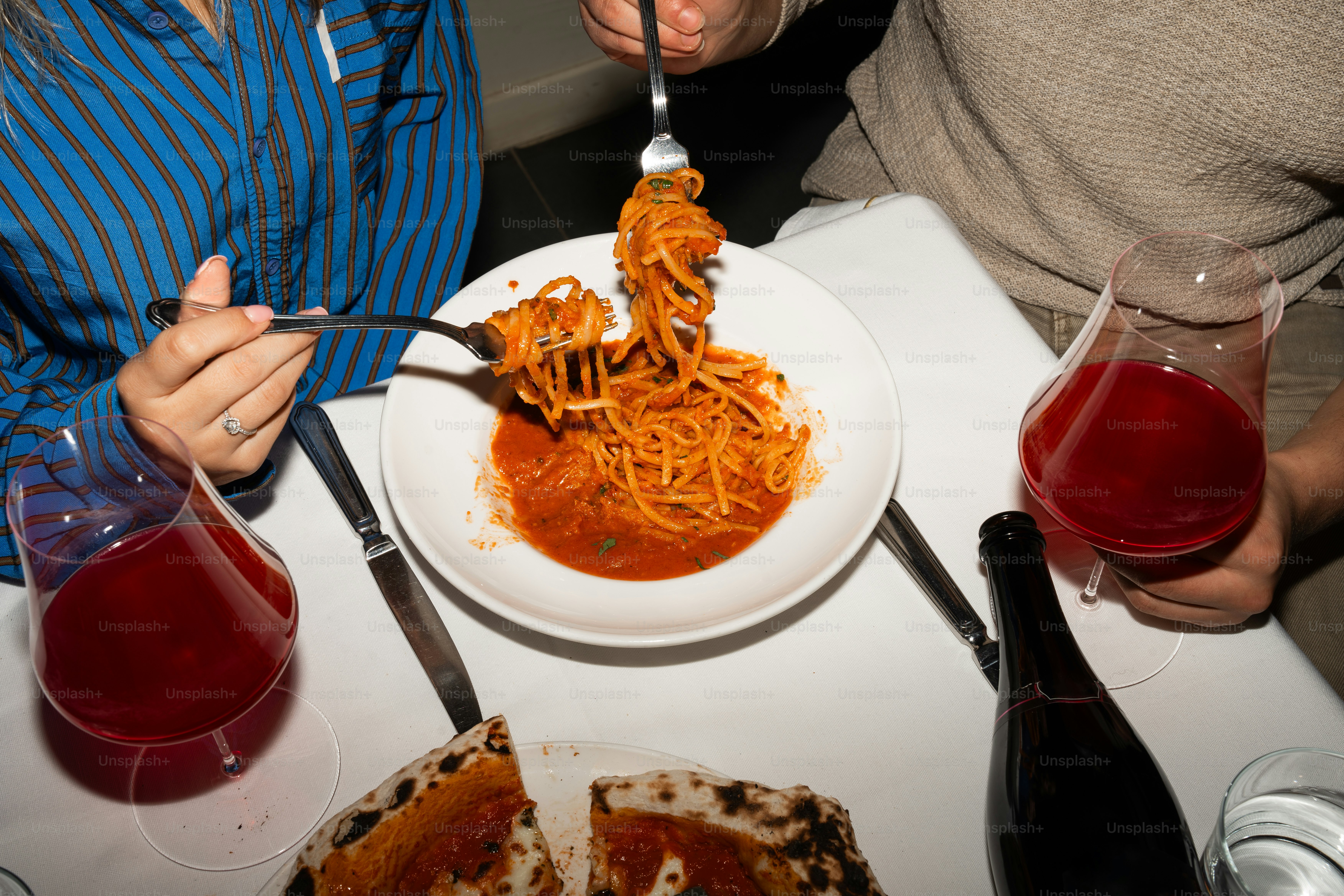 A man and a woman eating spaghetti at a restaurant