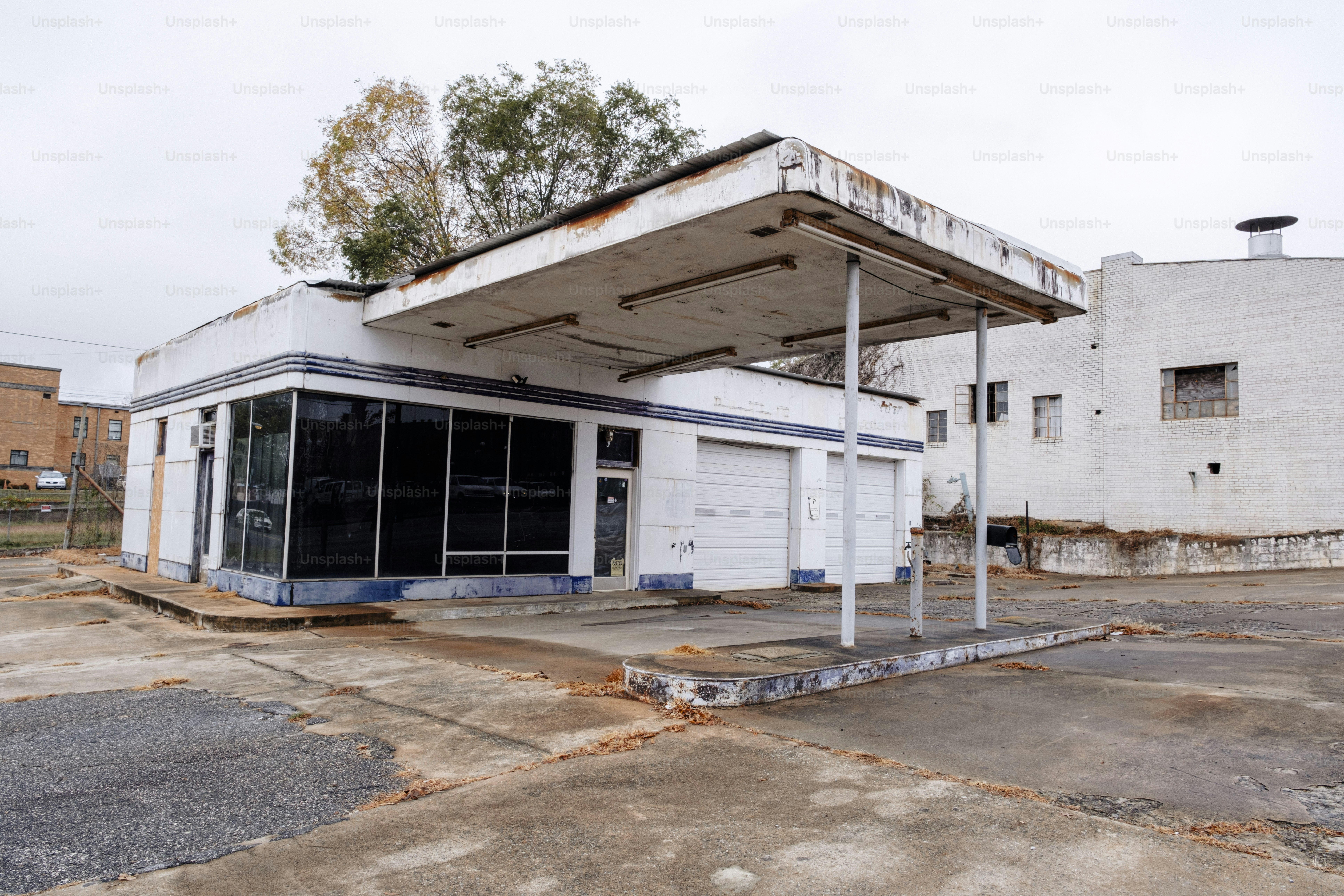 An abandoned gas station sits empty in a parking lot