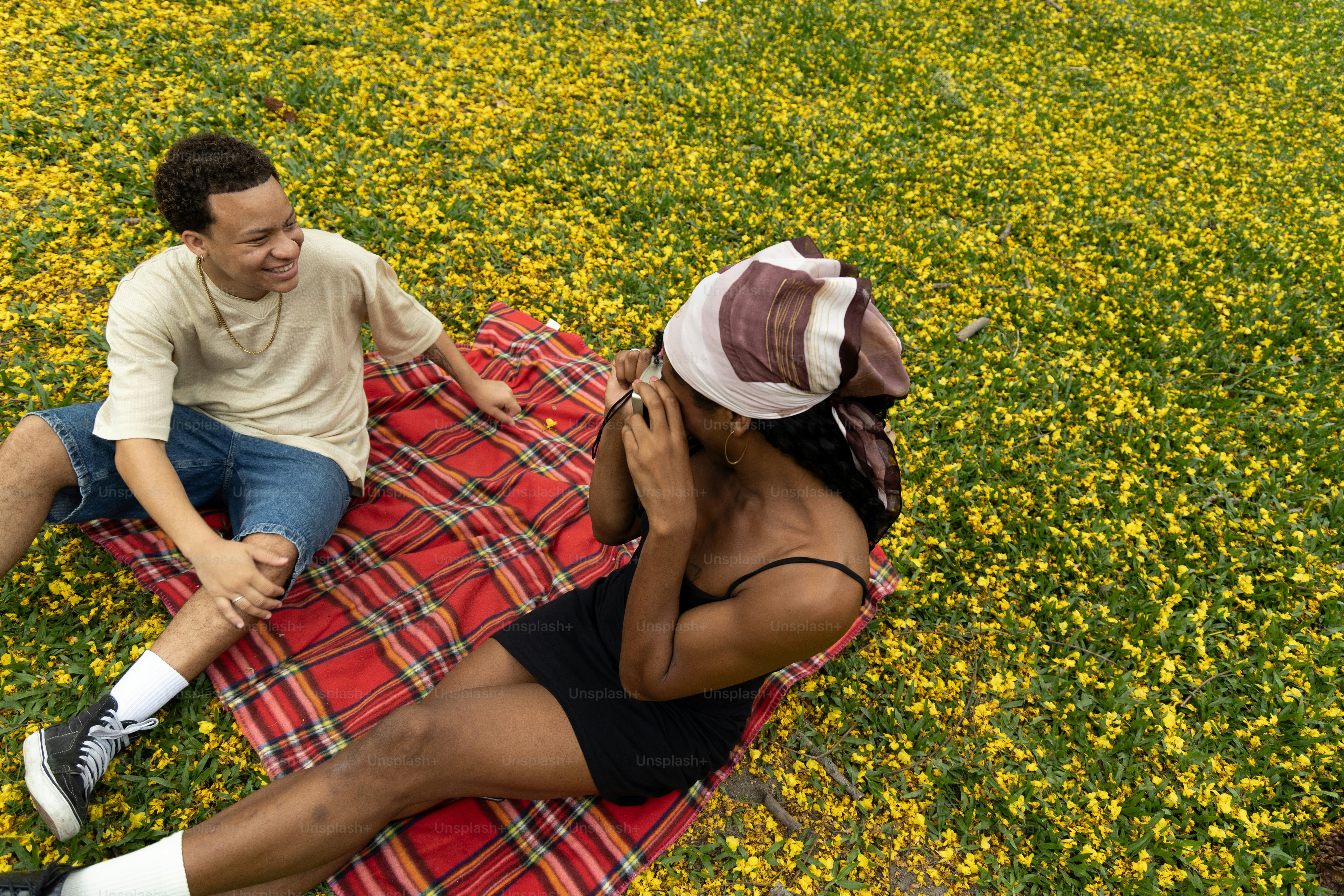 Un uomo e una donna seduti su una coperta in un campo di fiori