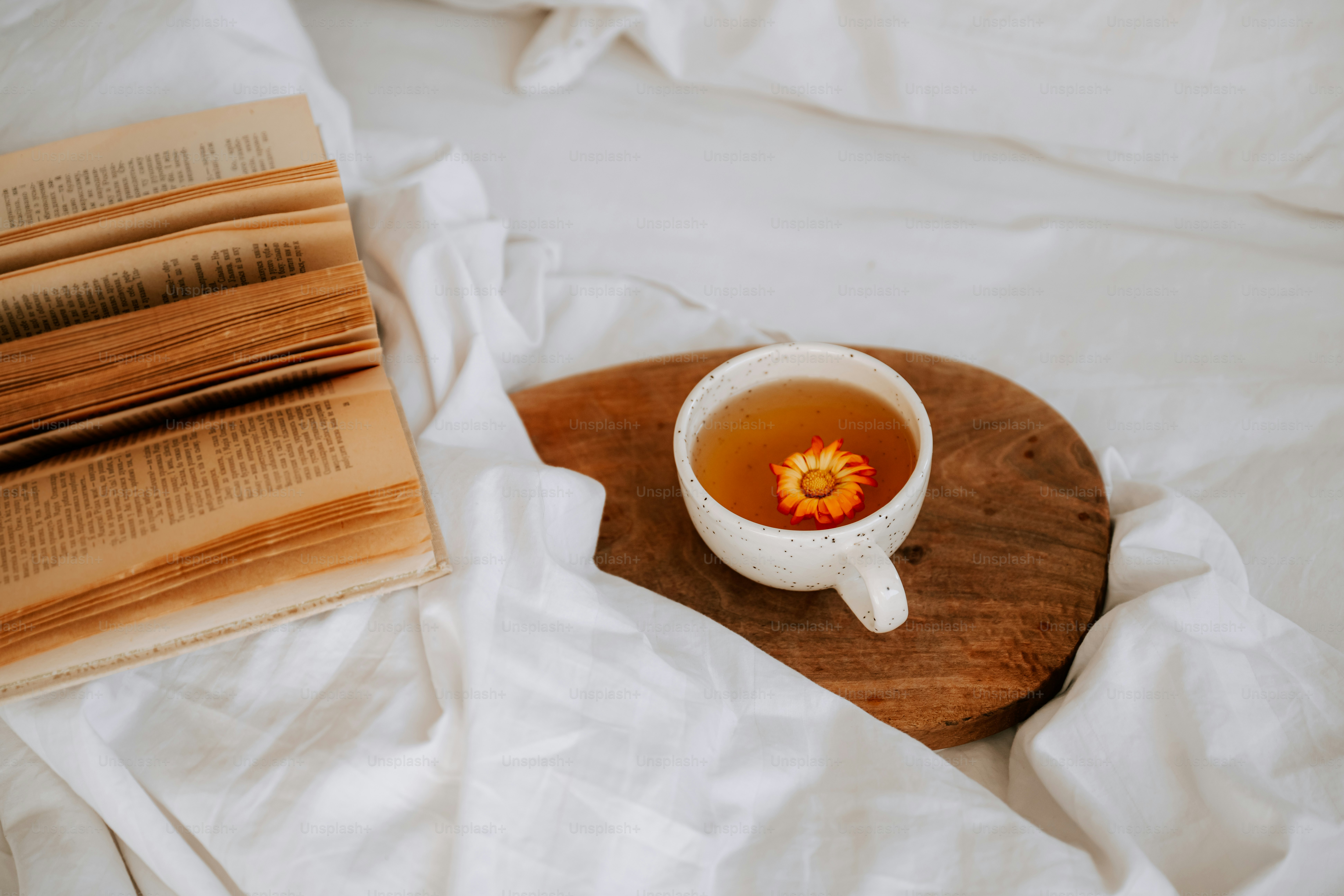 A cup of tea and a book on a bed