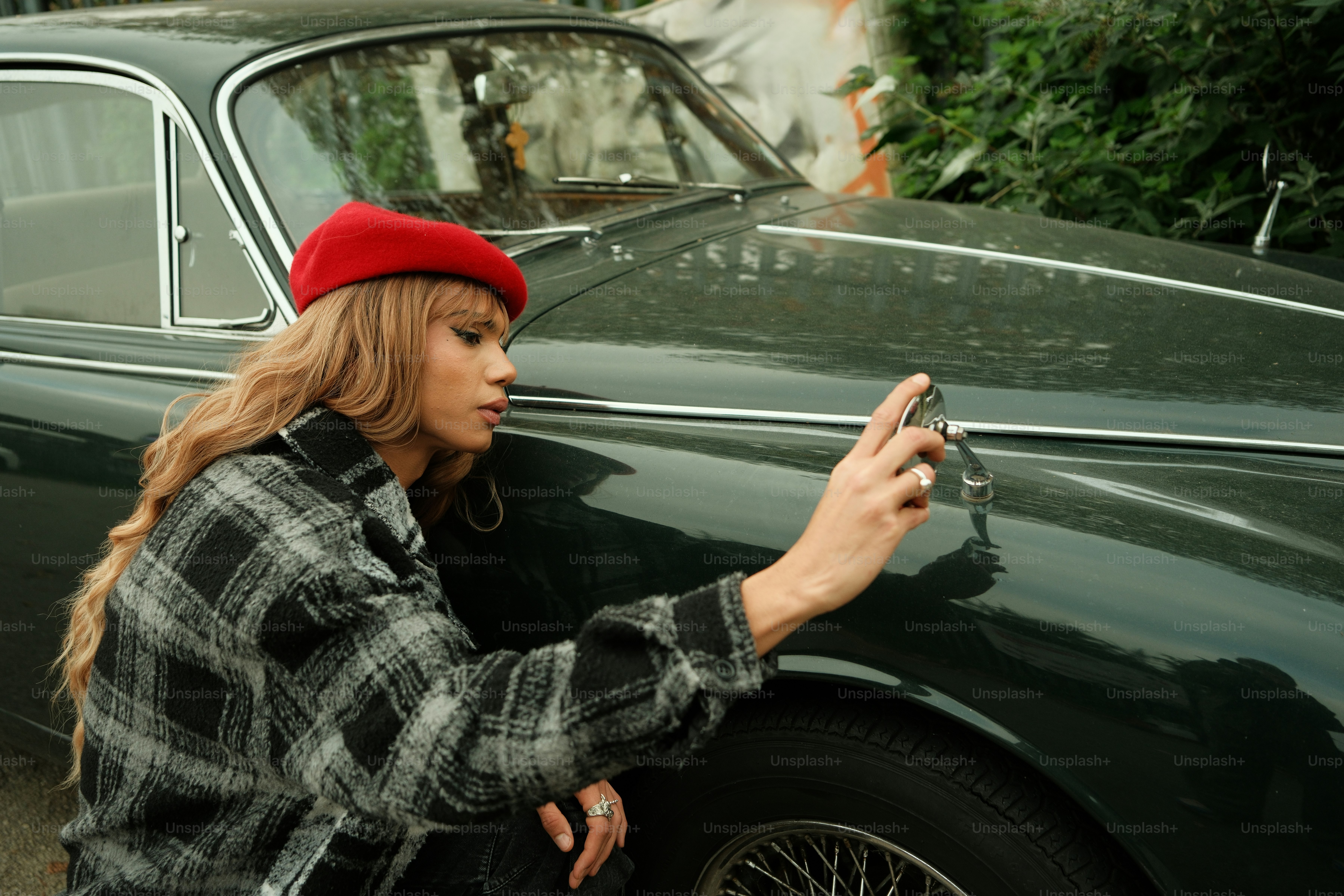 A woman leaning against a car holding a cell phone