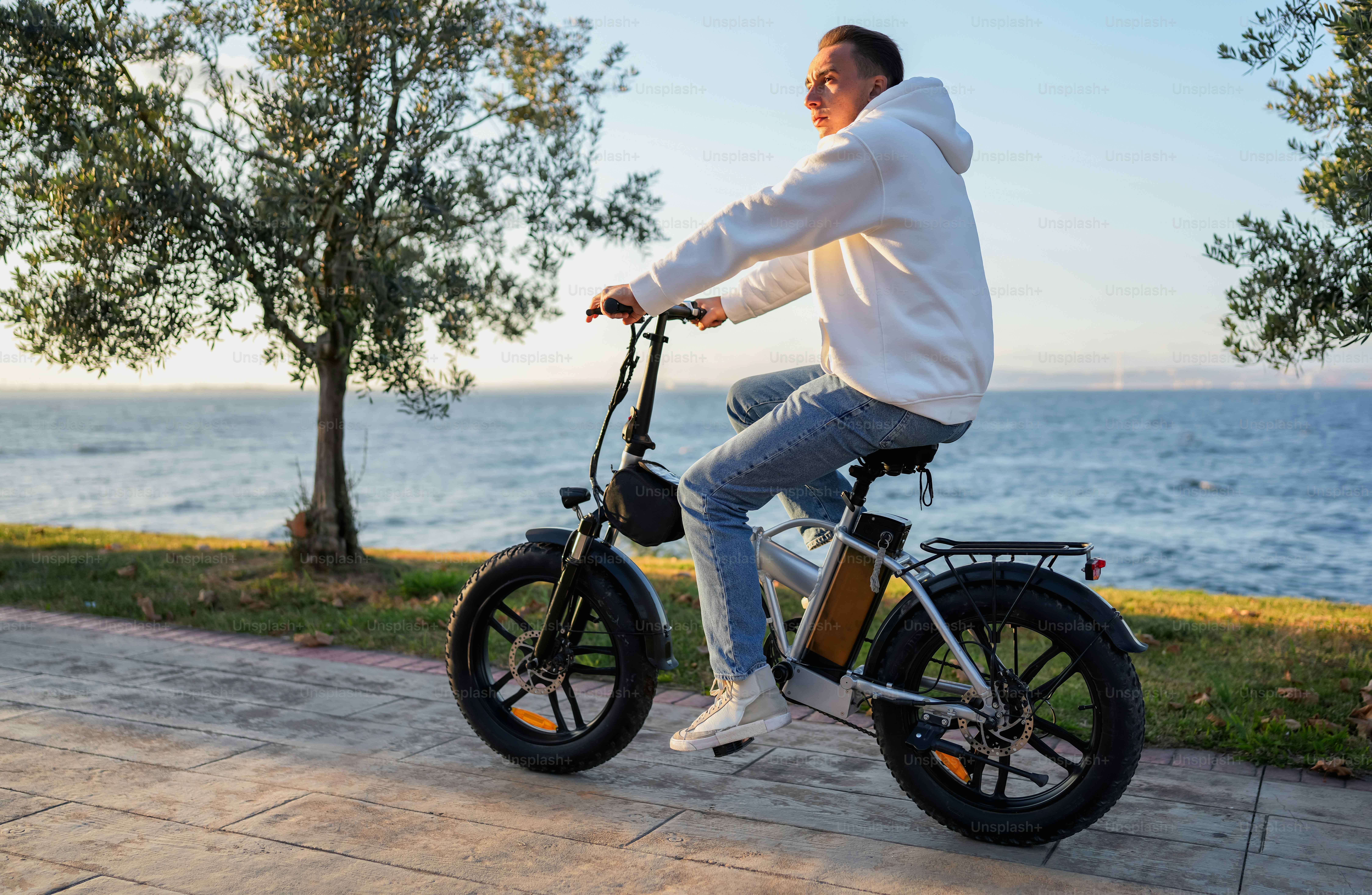 A man riding a bike down a sidewalk next to a lake