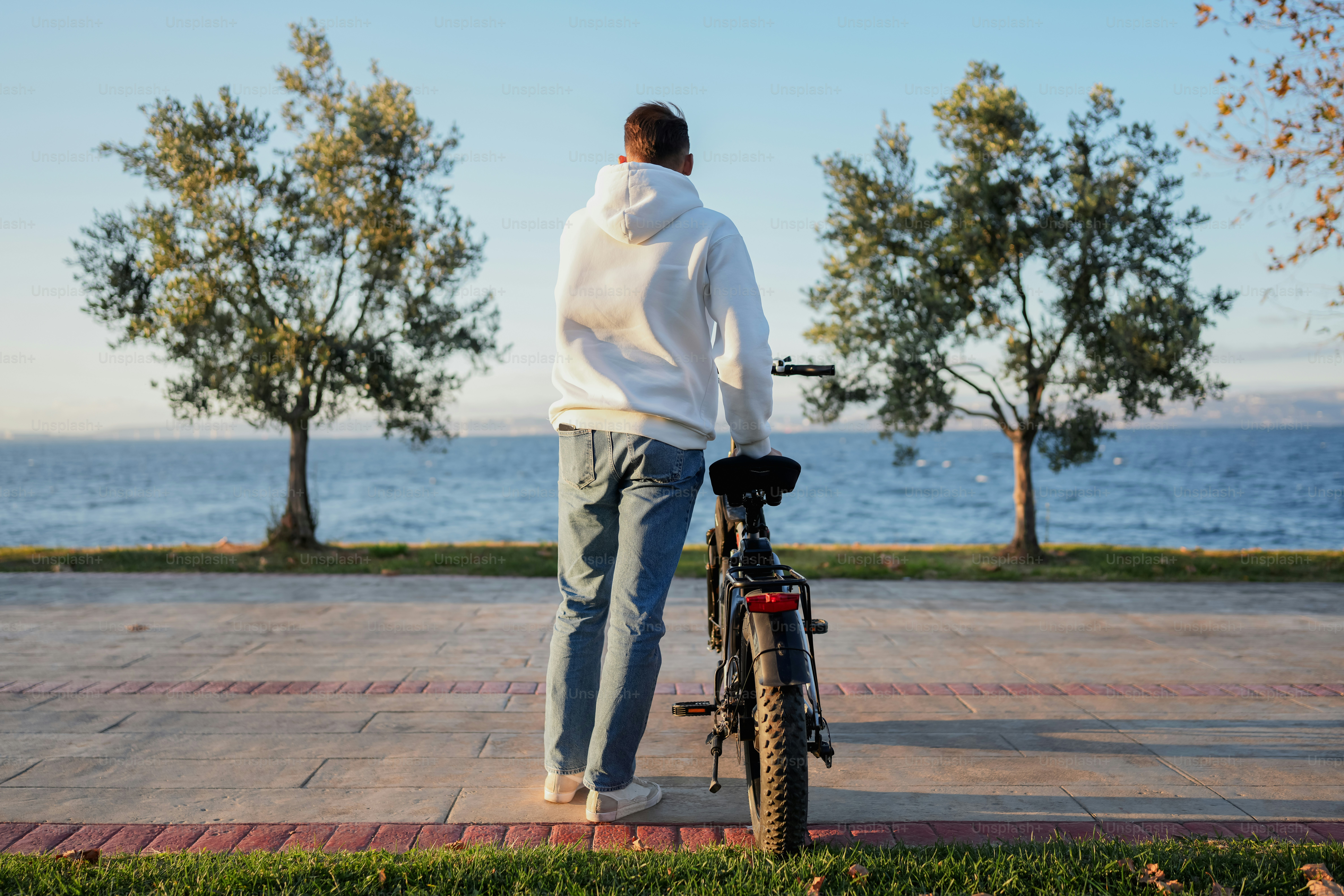 A man standing next to a bike on a sidewalk