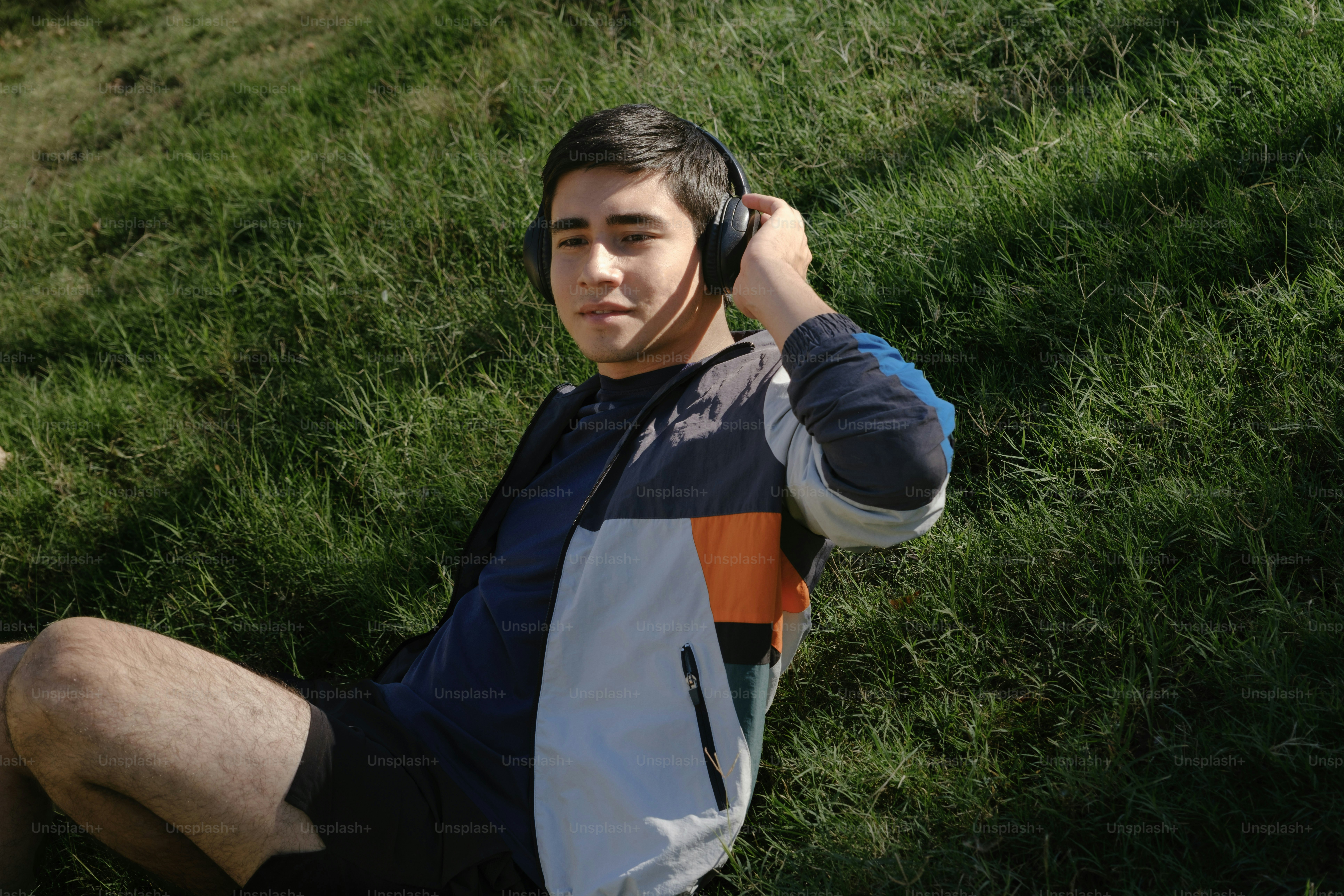 A man sitting in the grass with a cell phone to his ear