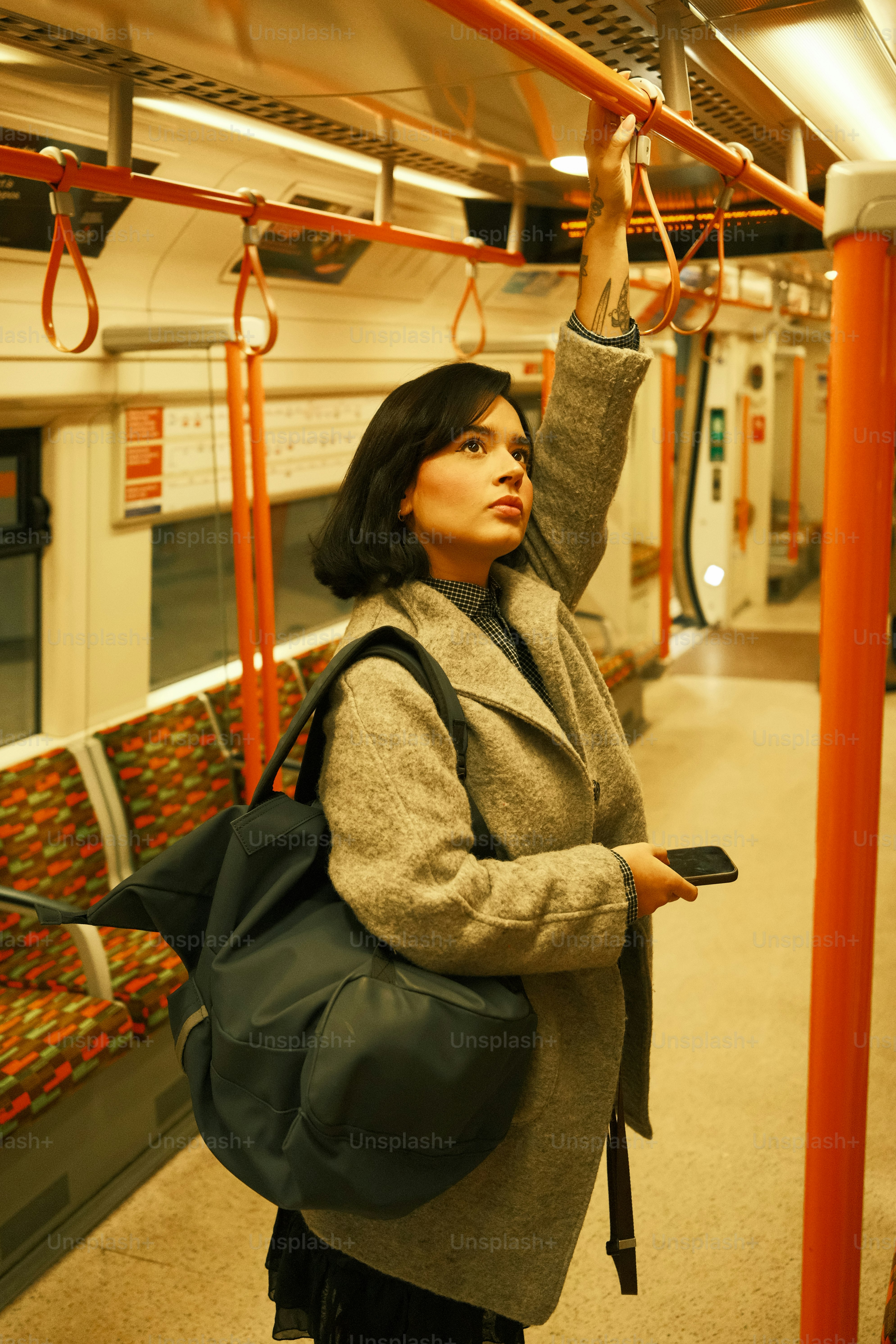 A woman standing on a train holding a cell phone