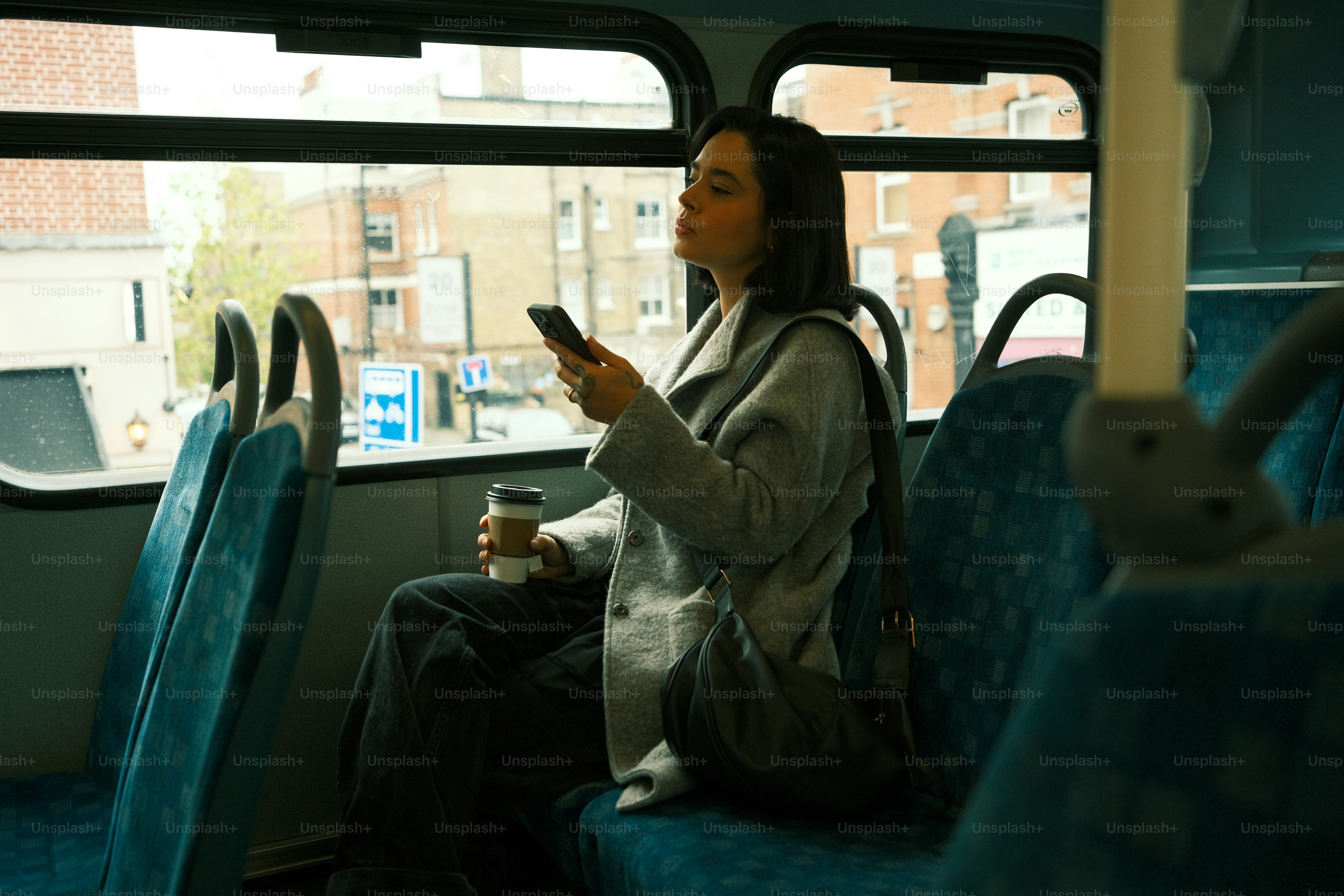 A woman sitting on a bus looking at her phone