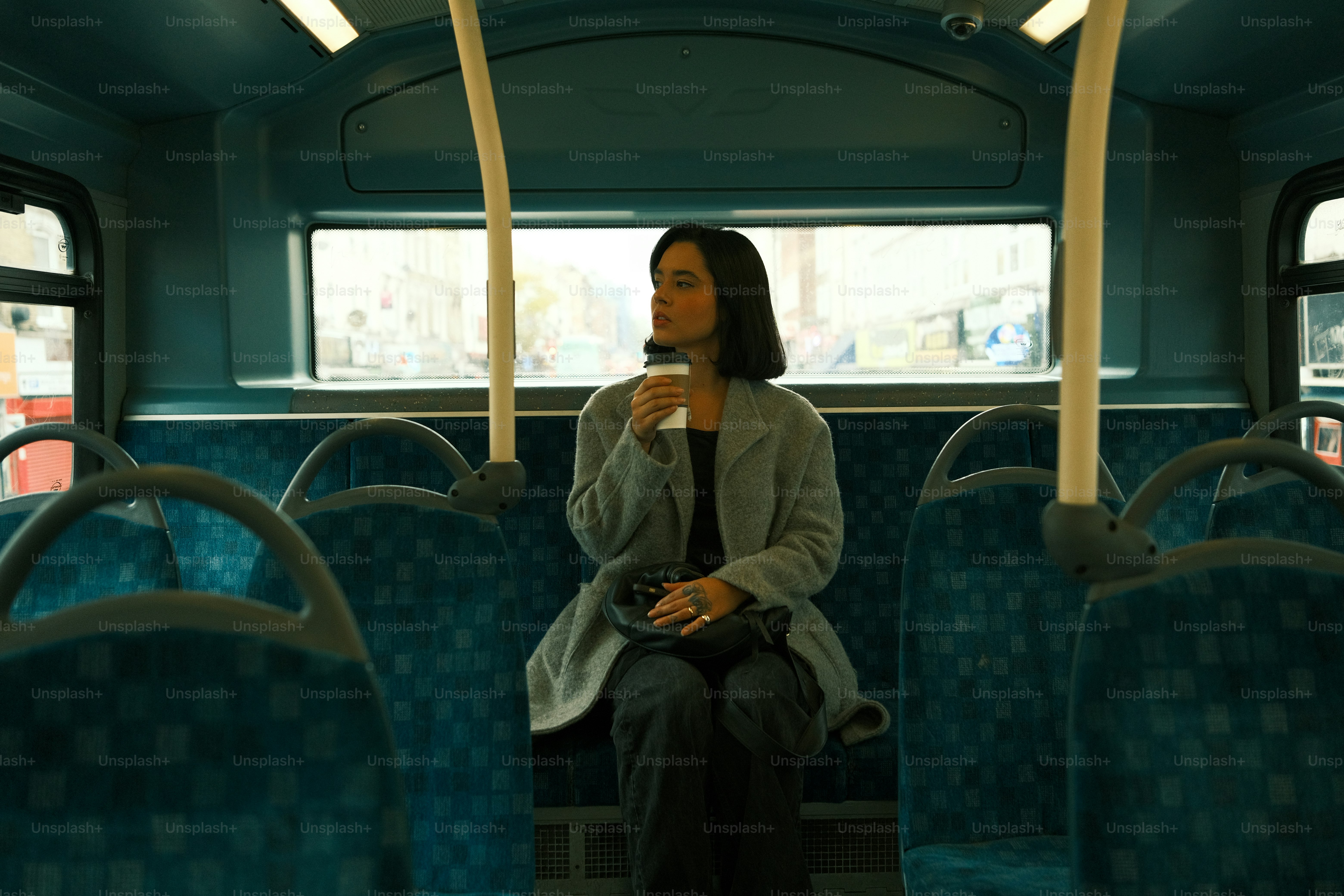 A woman sitting on a bus with a cup of coffee
