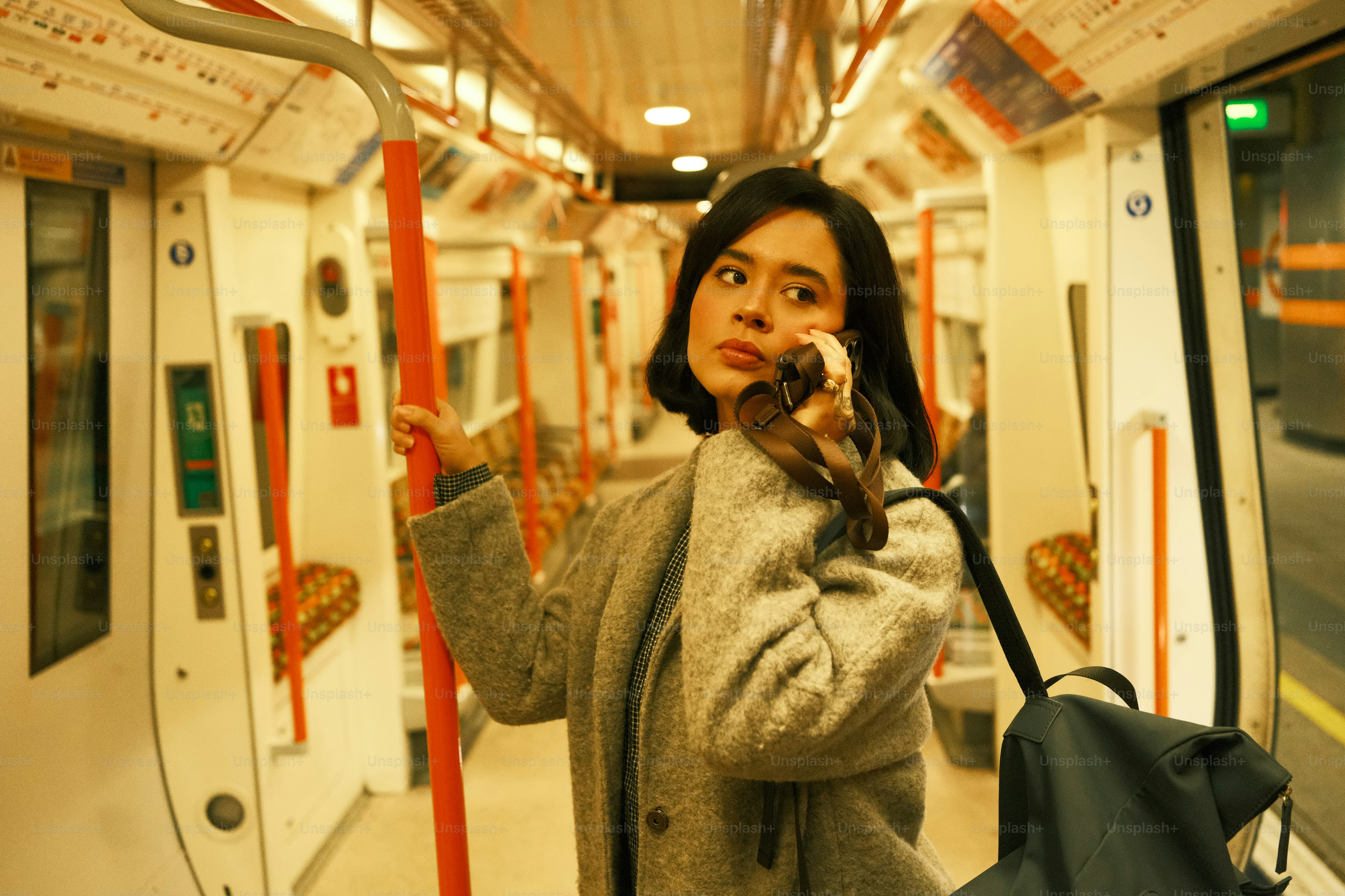 A woman standing on a subway train holding a cell phone