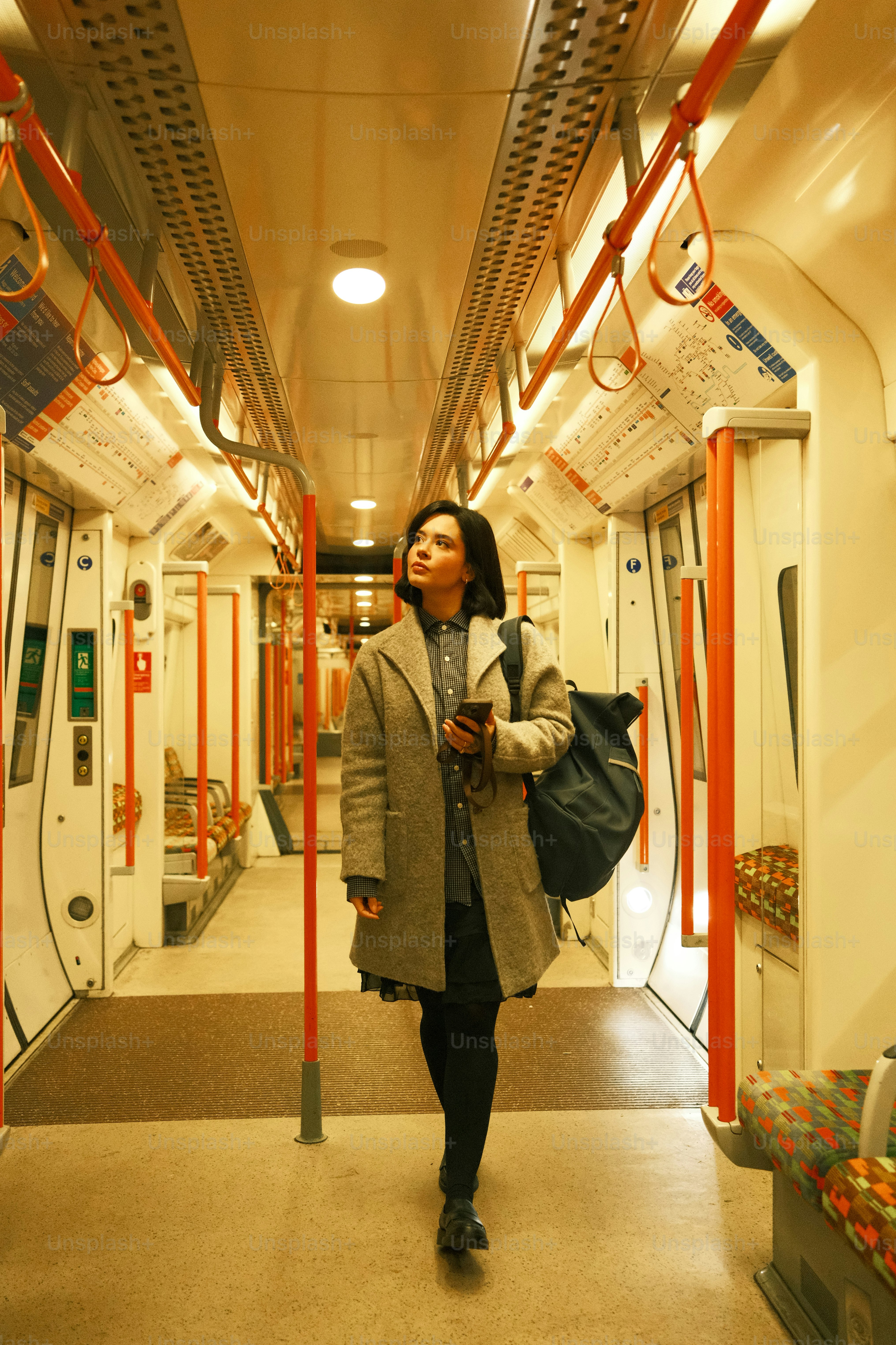 A woman is walking down a subway train