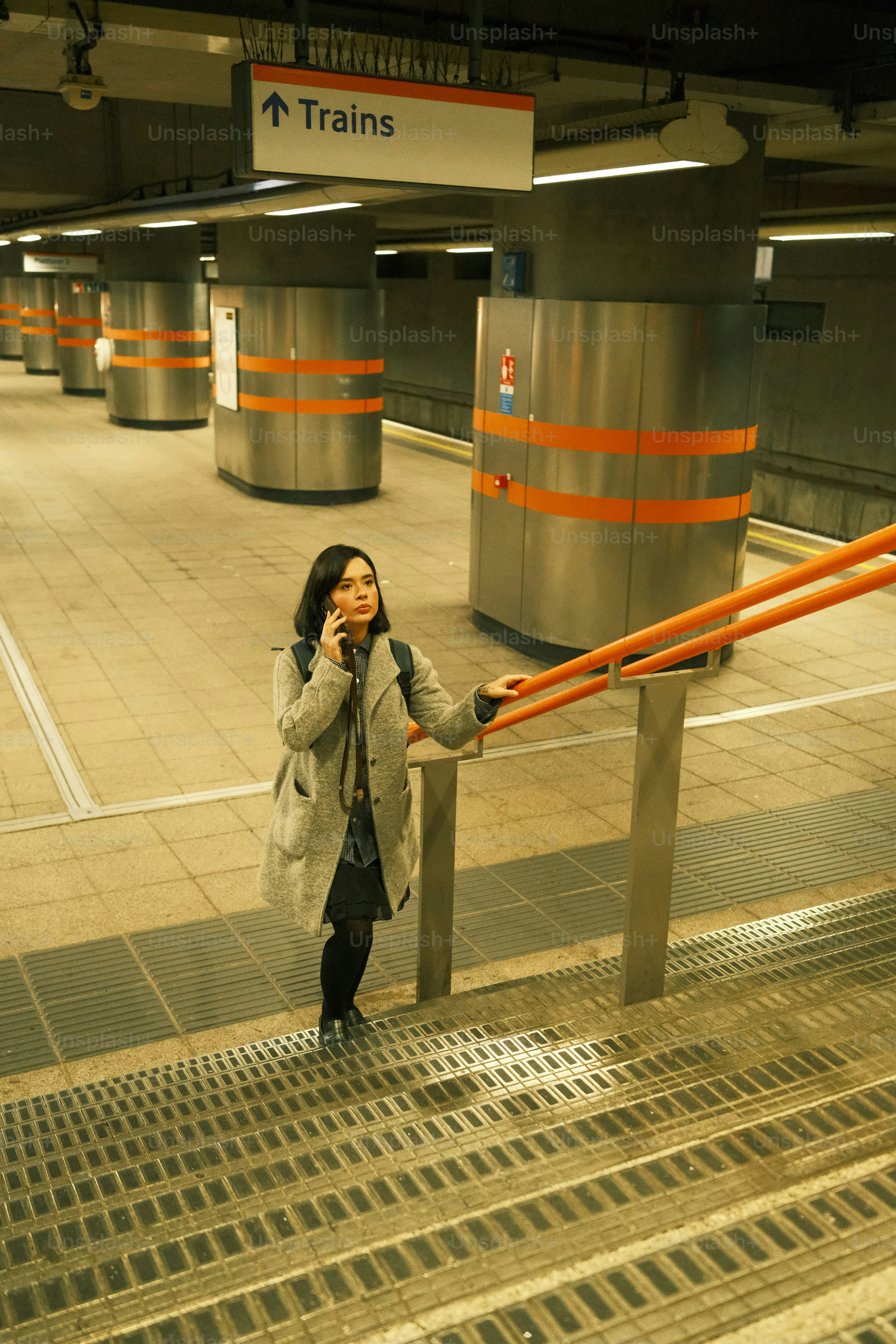 A woman talking on a cell phone while standing on a train platform