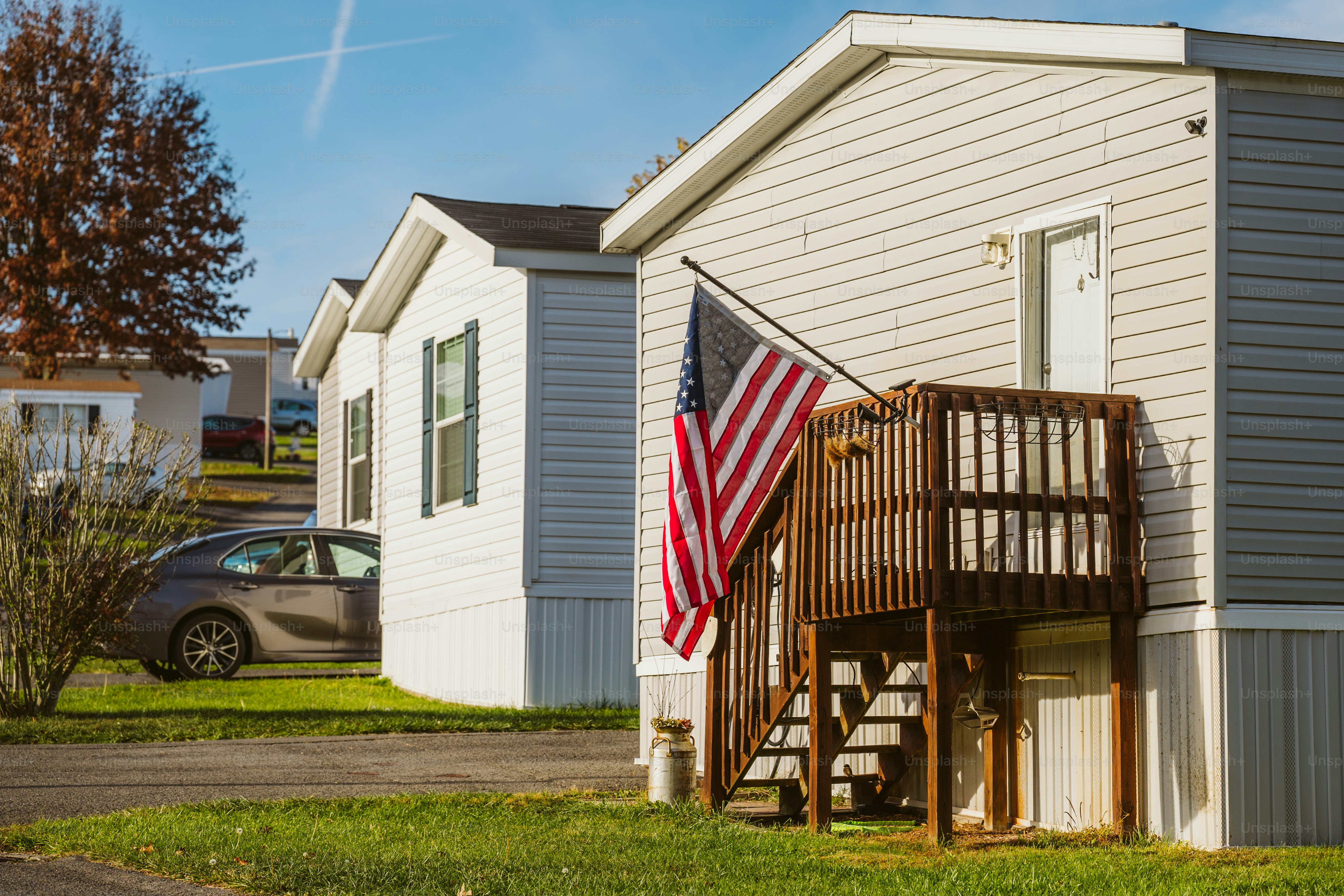 A mobile home with an american flag on the porch
