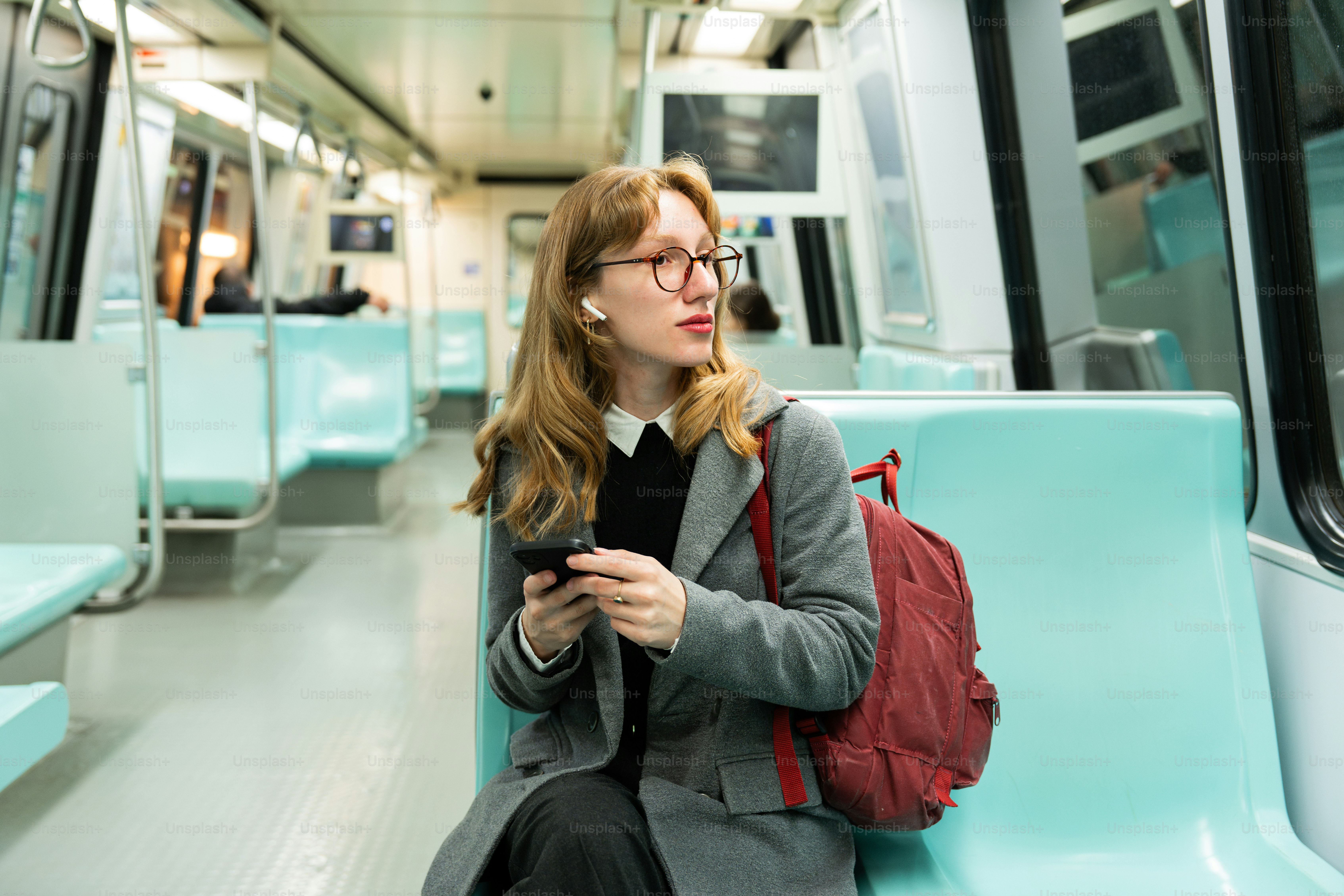 A woman sitting on a train looking at her phone