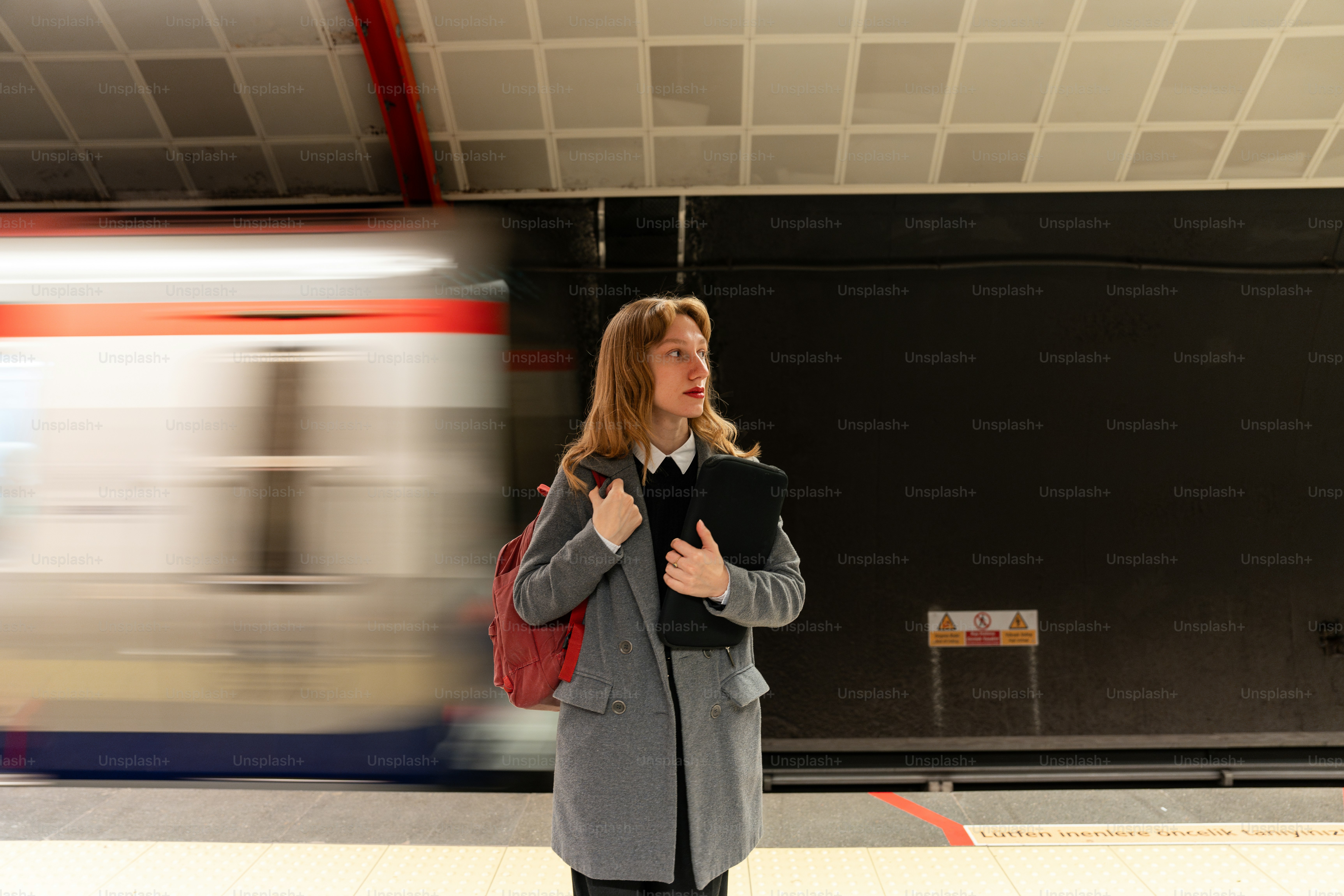 A woman standing in a subway station holding a book