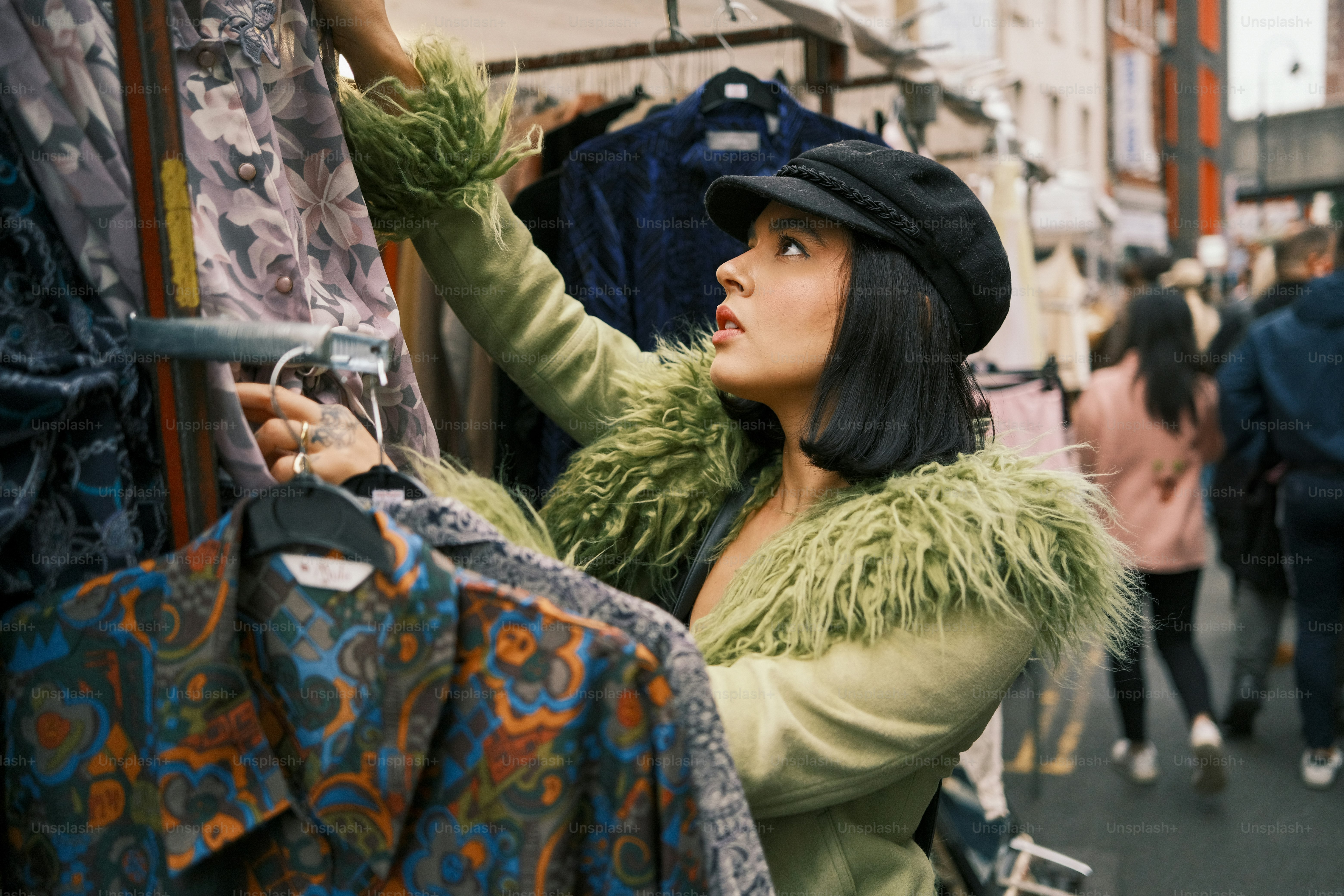 A woman in a green coat and hat looking up at the sky