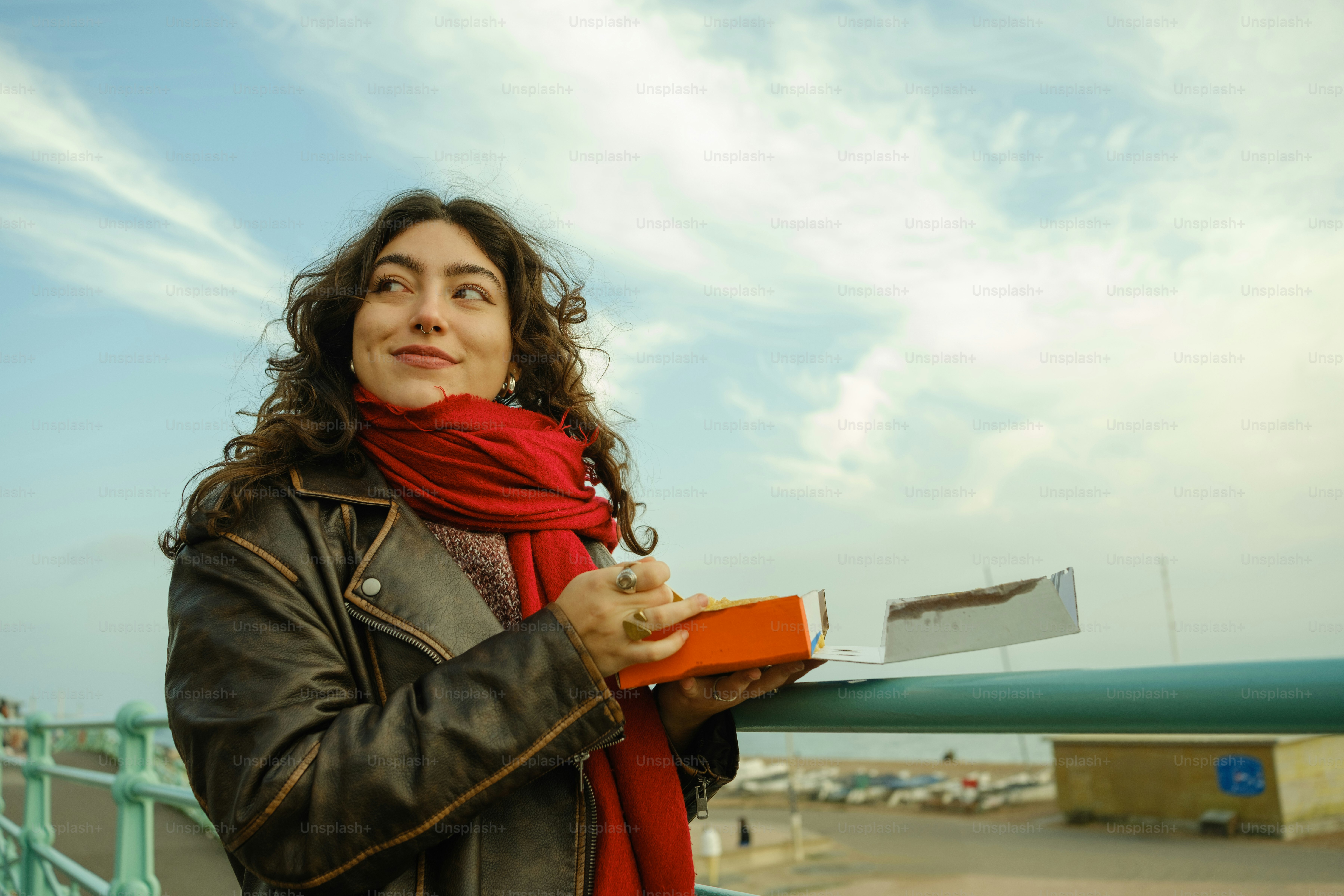 A woman standing on a bridge with a red scarf around her neck