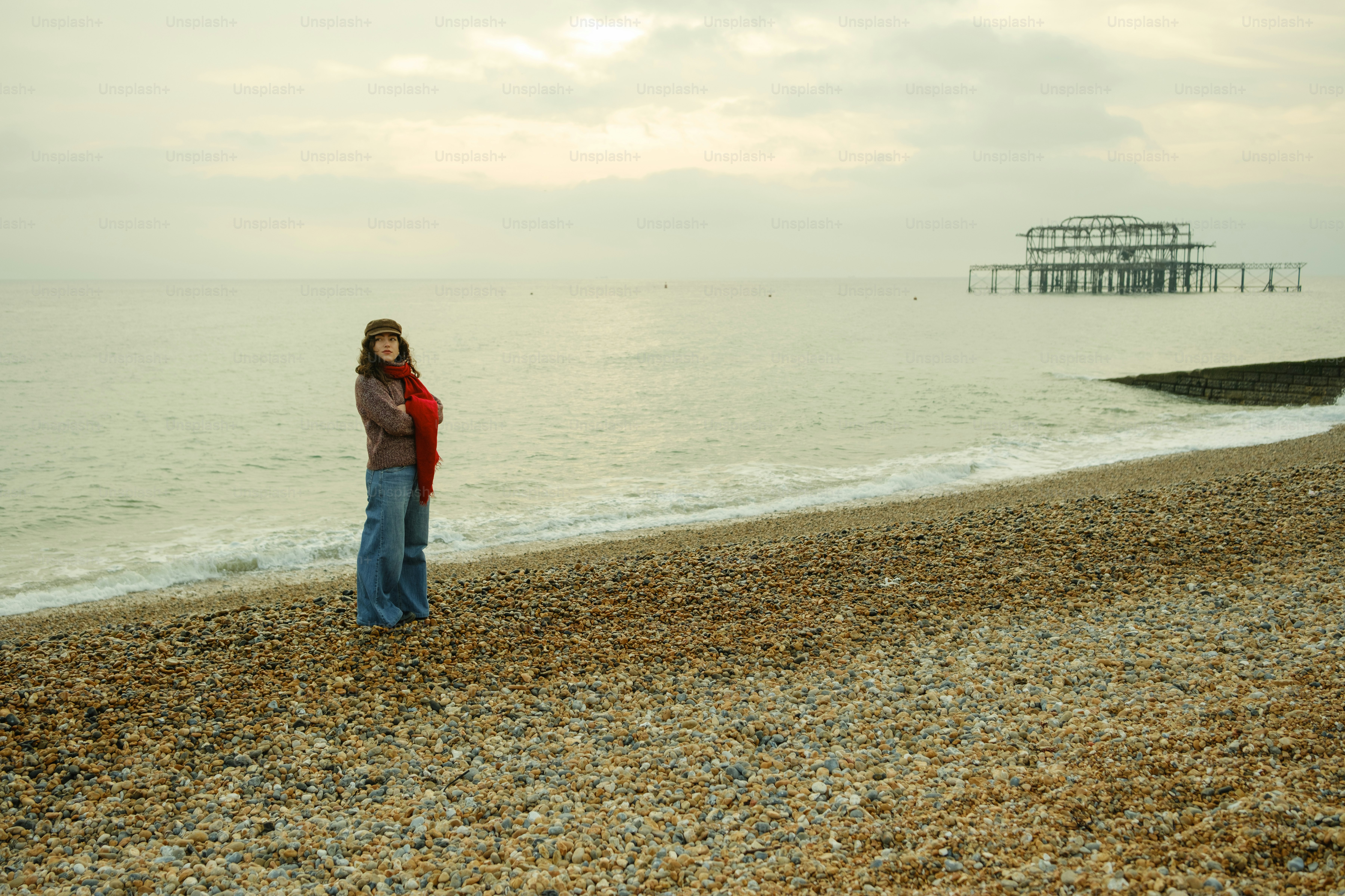 A woman standing on top of a beach next to the ocean