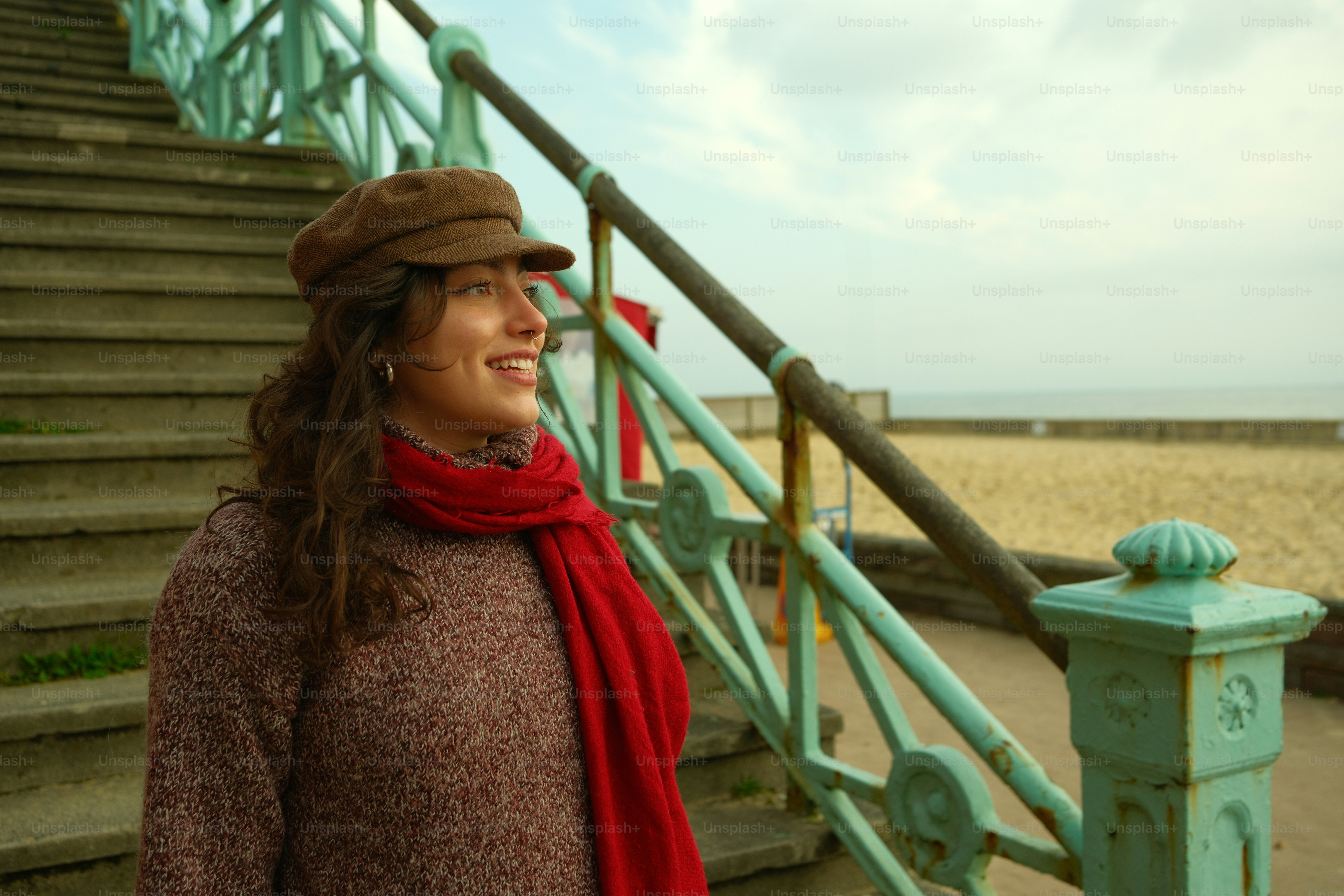 A woman in a hat and scarf standing next to a set of stairs