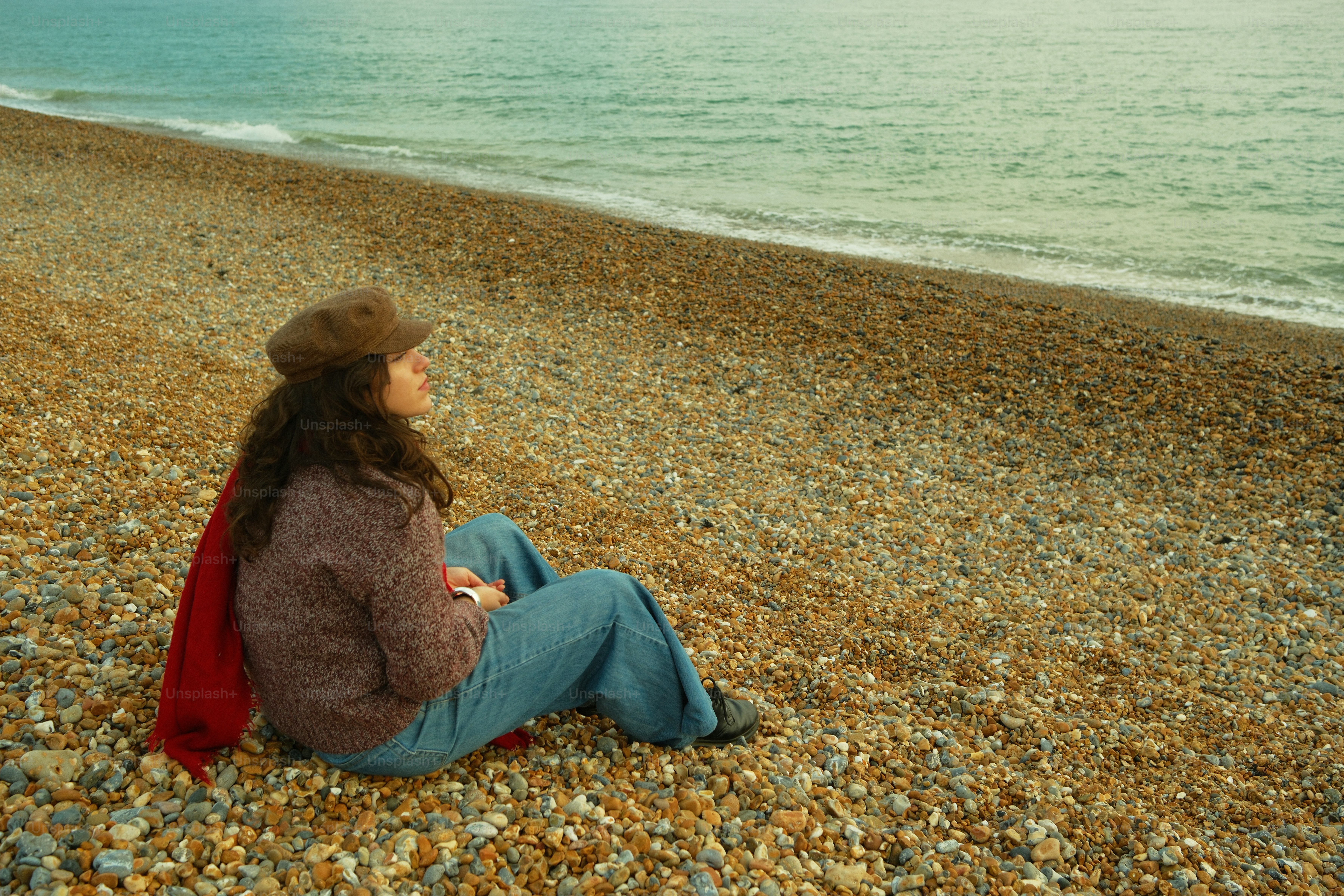 A woman sitting on a beach next to the ocean