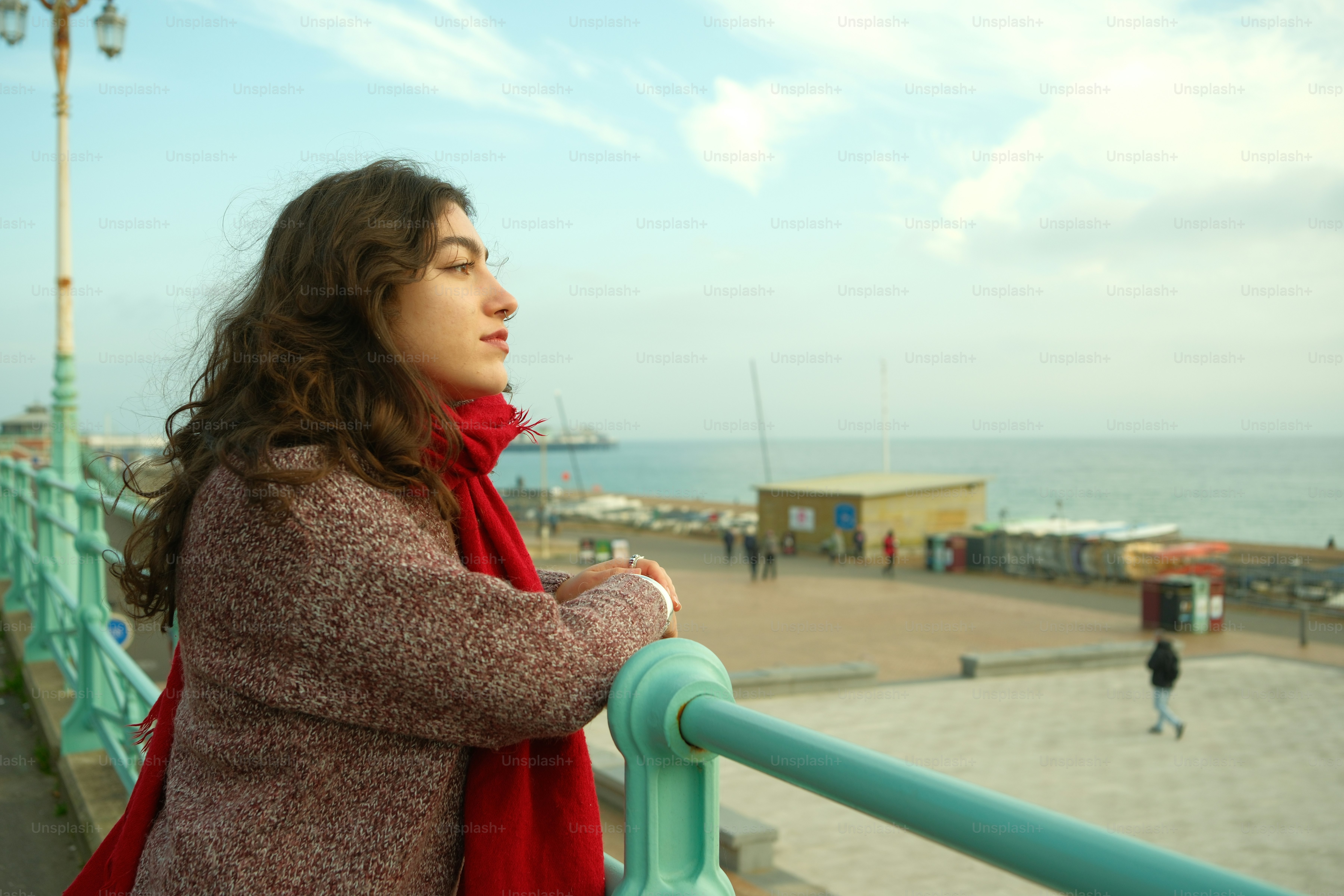 A woman standing on a balcony next to the ocean