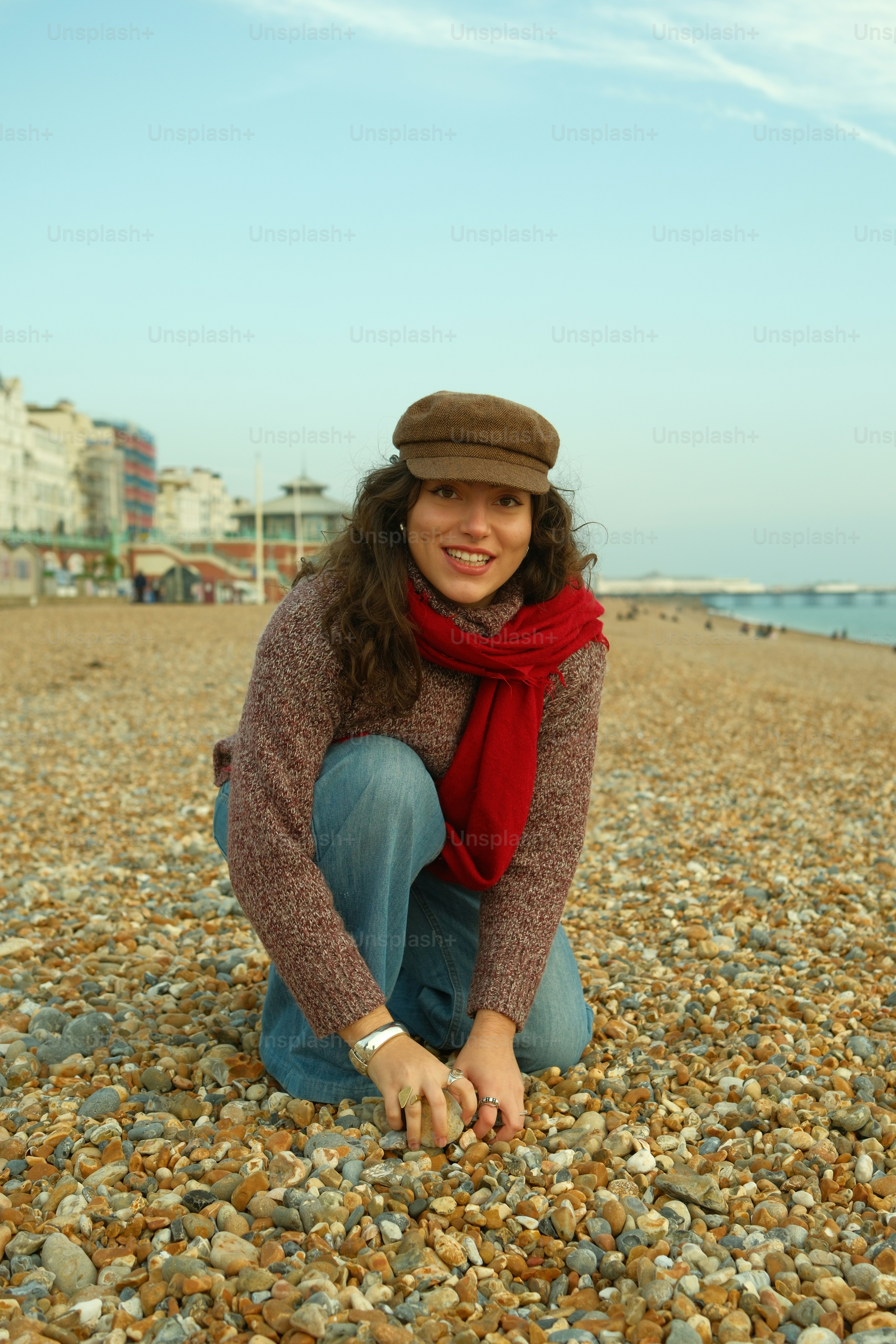 A woman kneeling down on a rocky beach