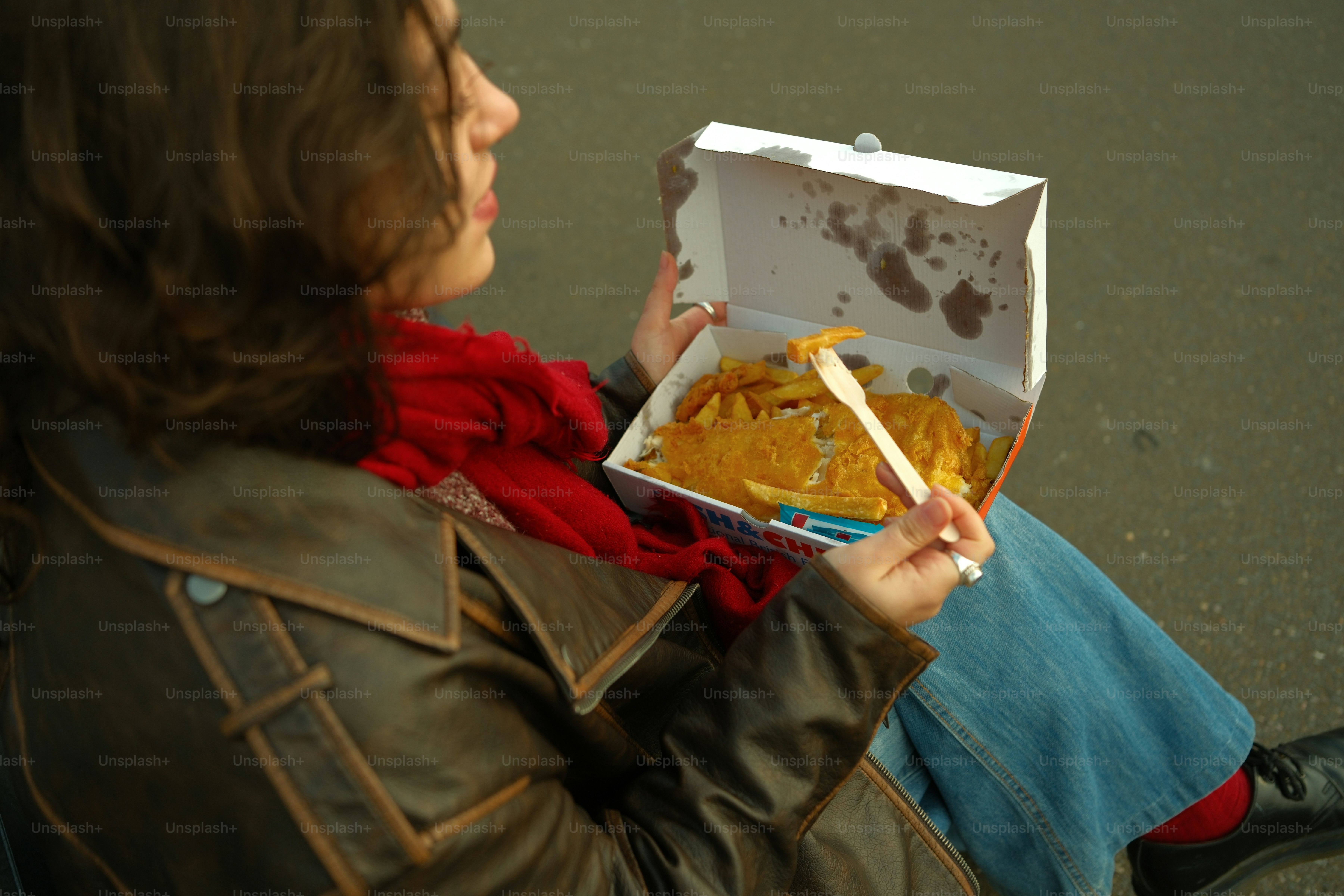 A woman sitting on the ground holding a box of food