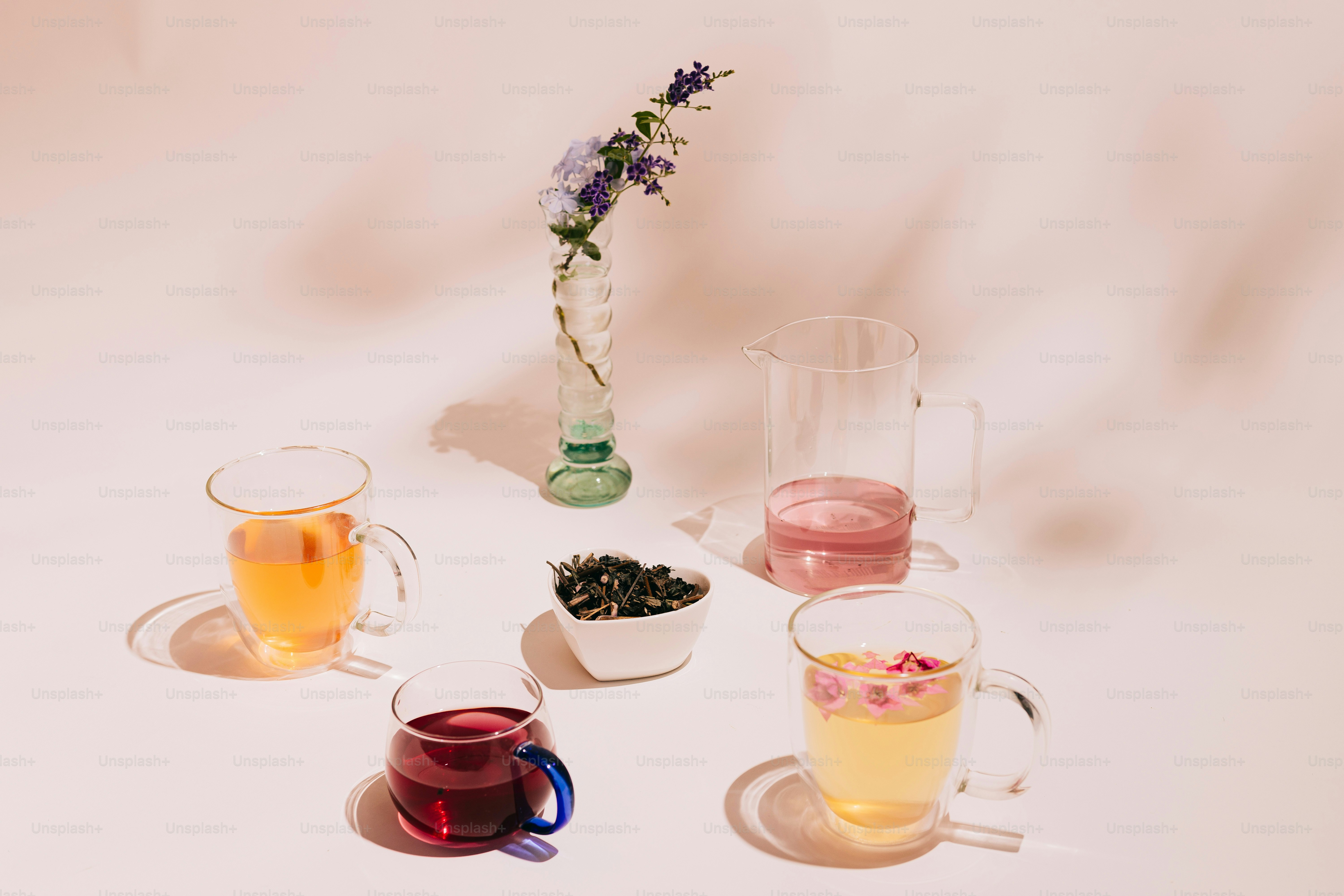 A white table topped with cups and vases filled with flowers