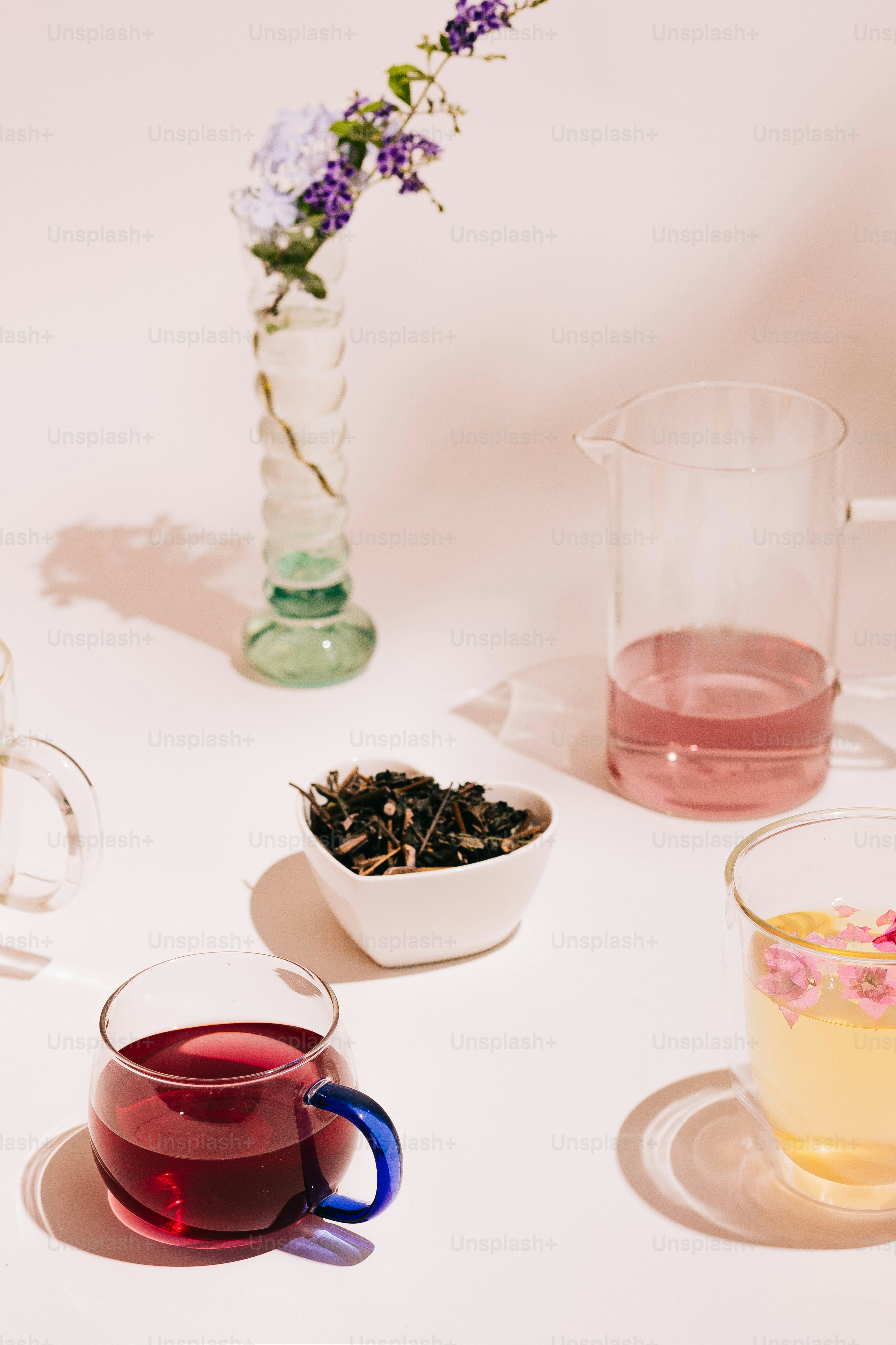 A white table topped with glasses and cups filled with liquid