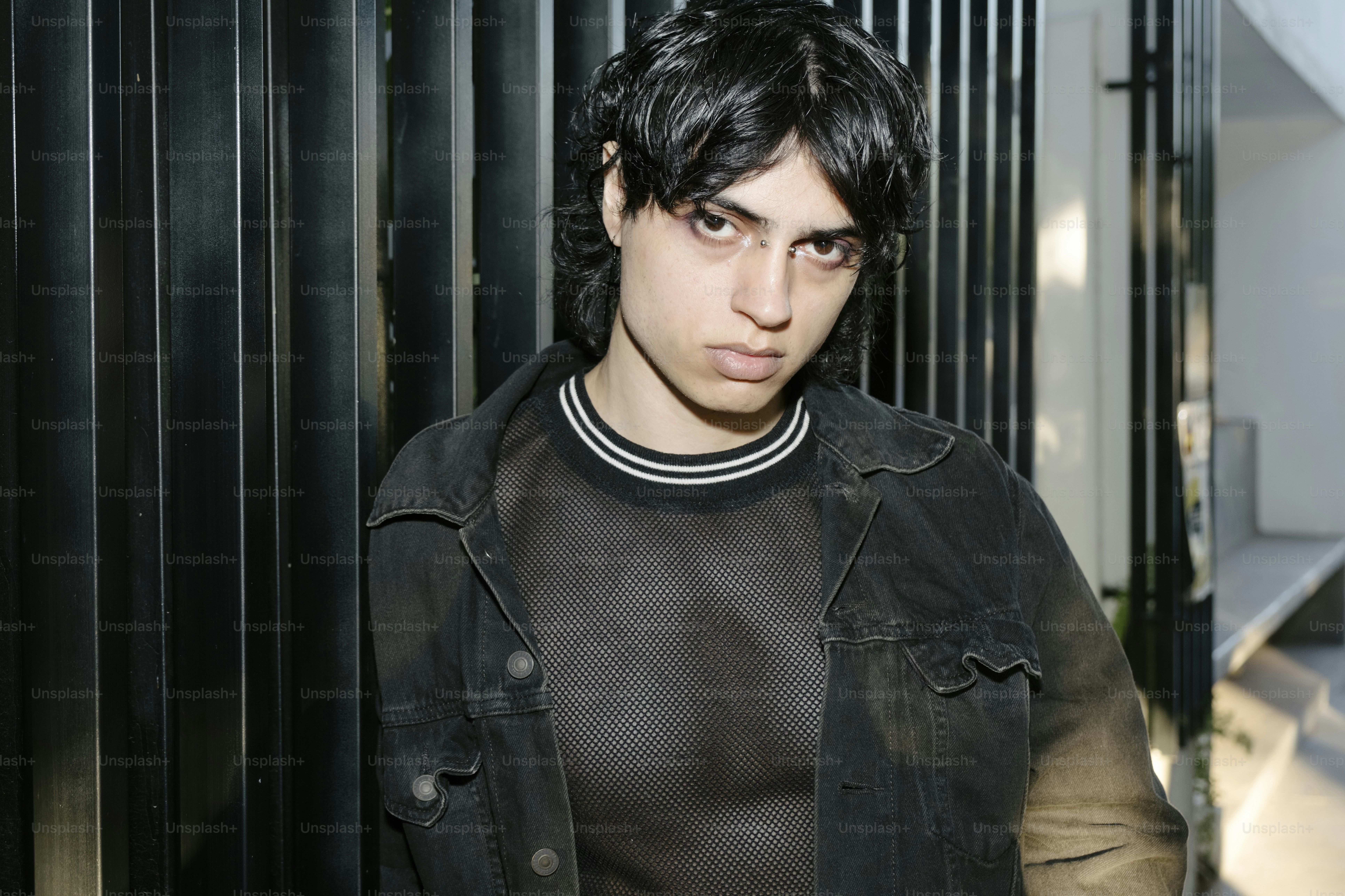 A man in a black jacket standing next to a black fence