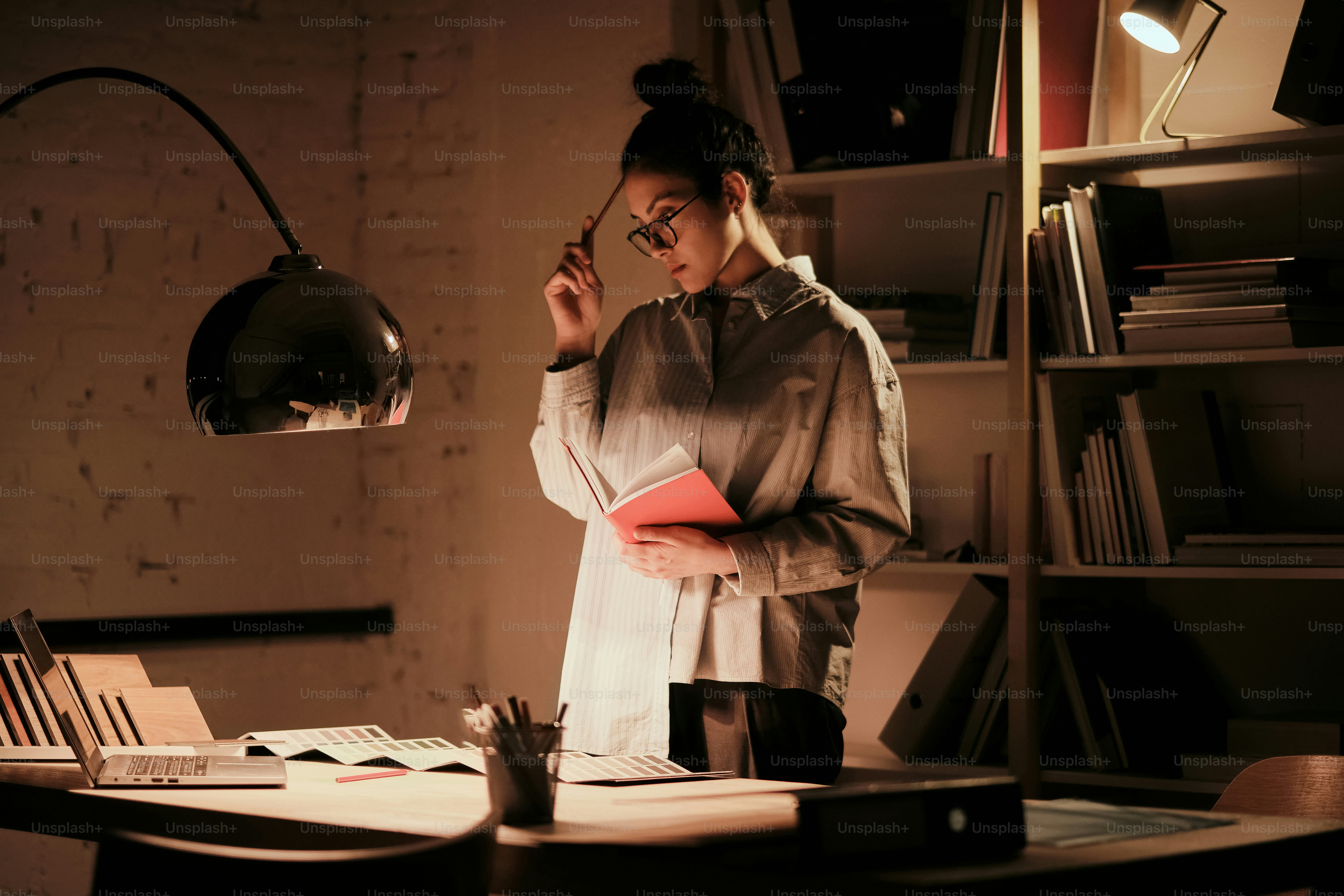 A woman standing in front of a desk with a lamp on it