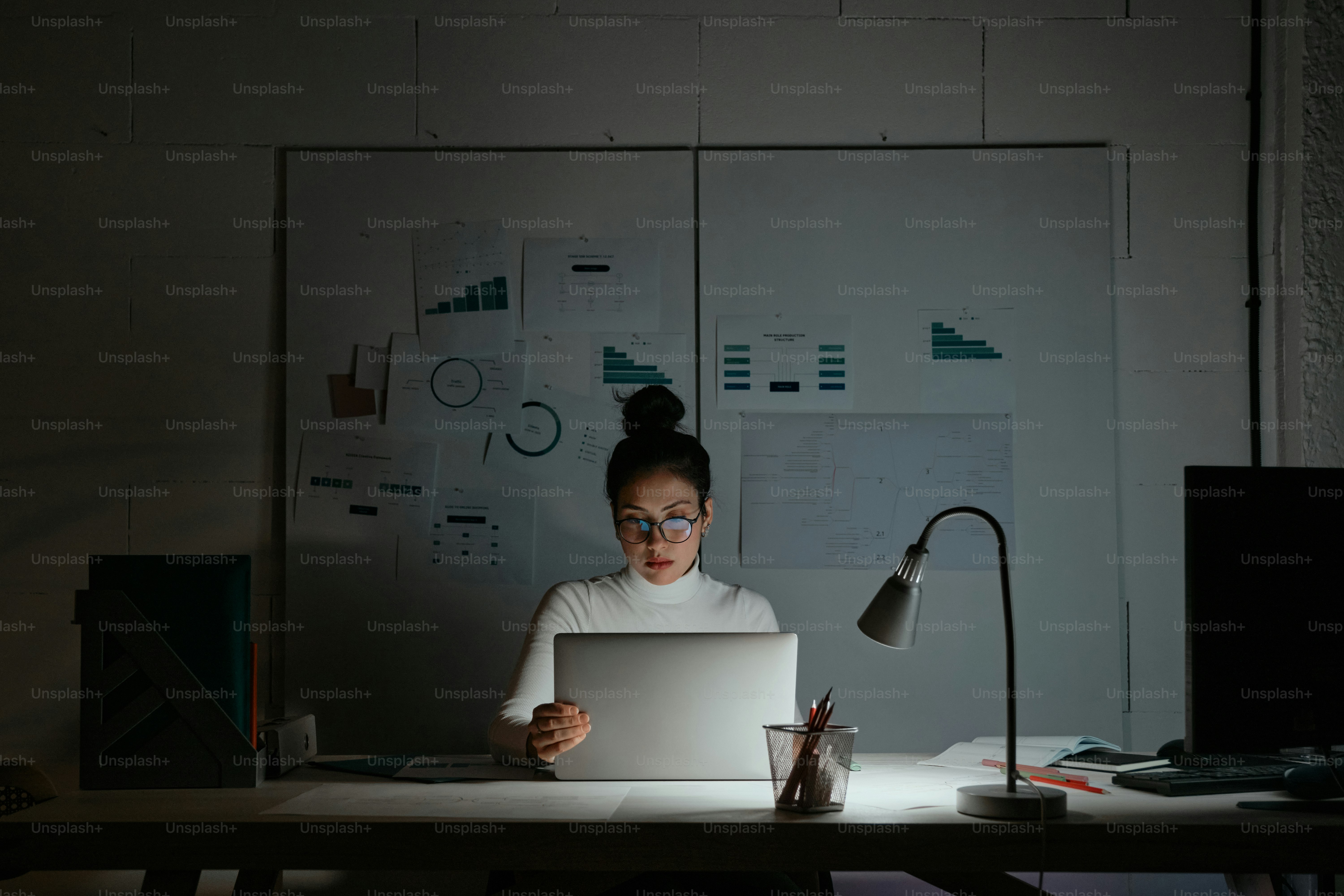 A woman sitting at a desk in front of a laptop computer