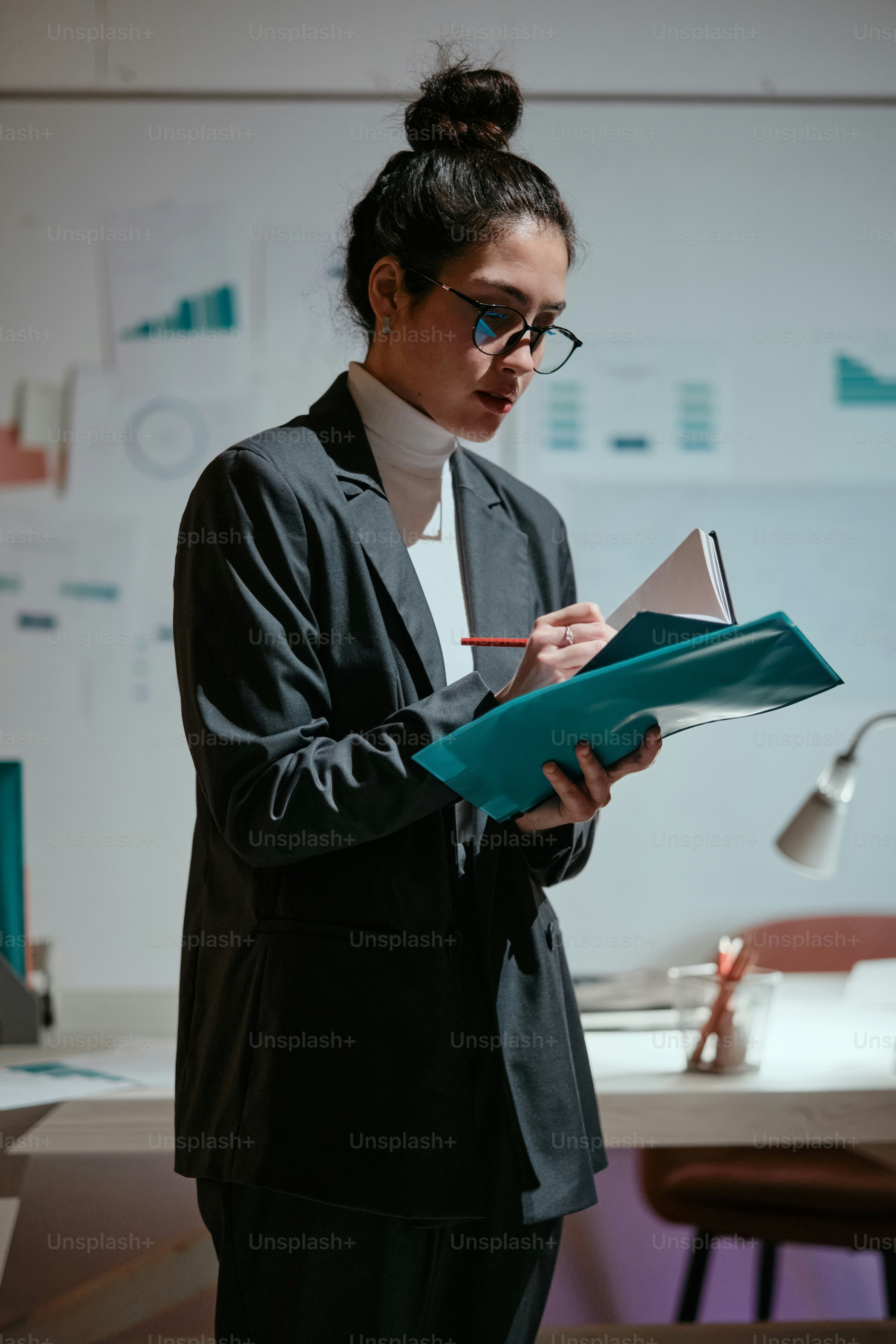 A woman standing in front of a desk holding a book