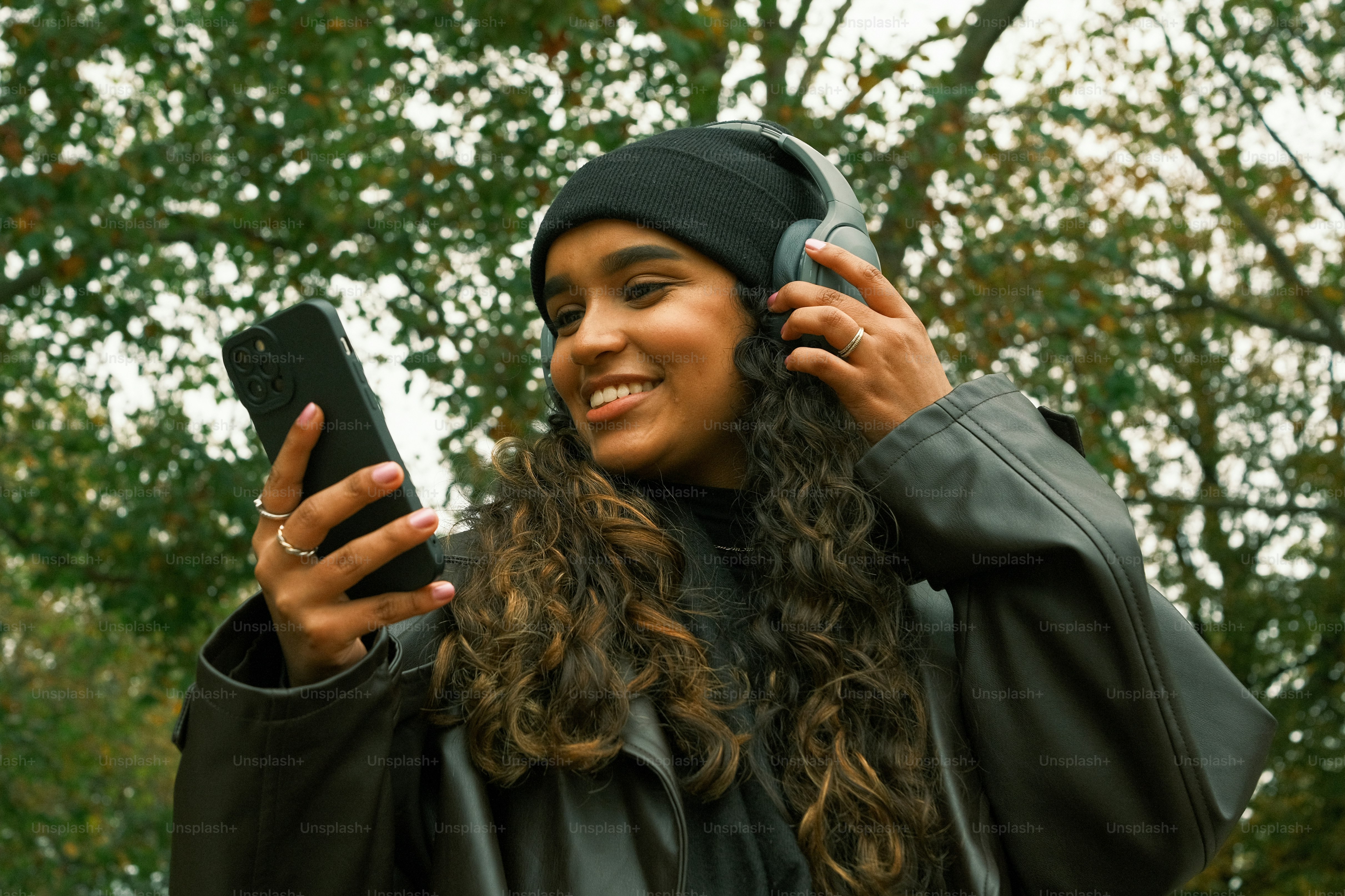 Seorang wanita dengan gaun kelulusan memegang ponsel