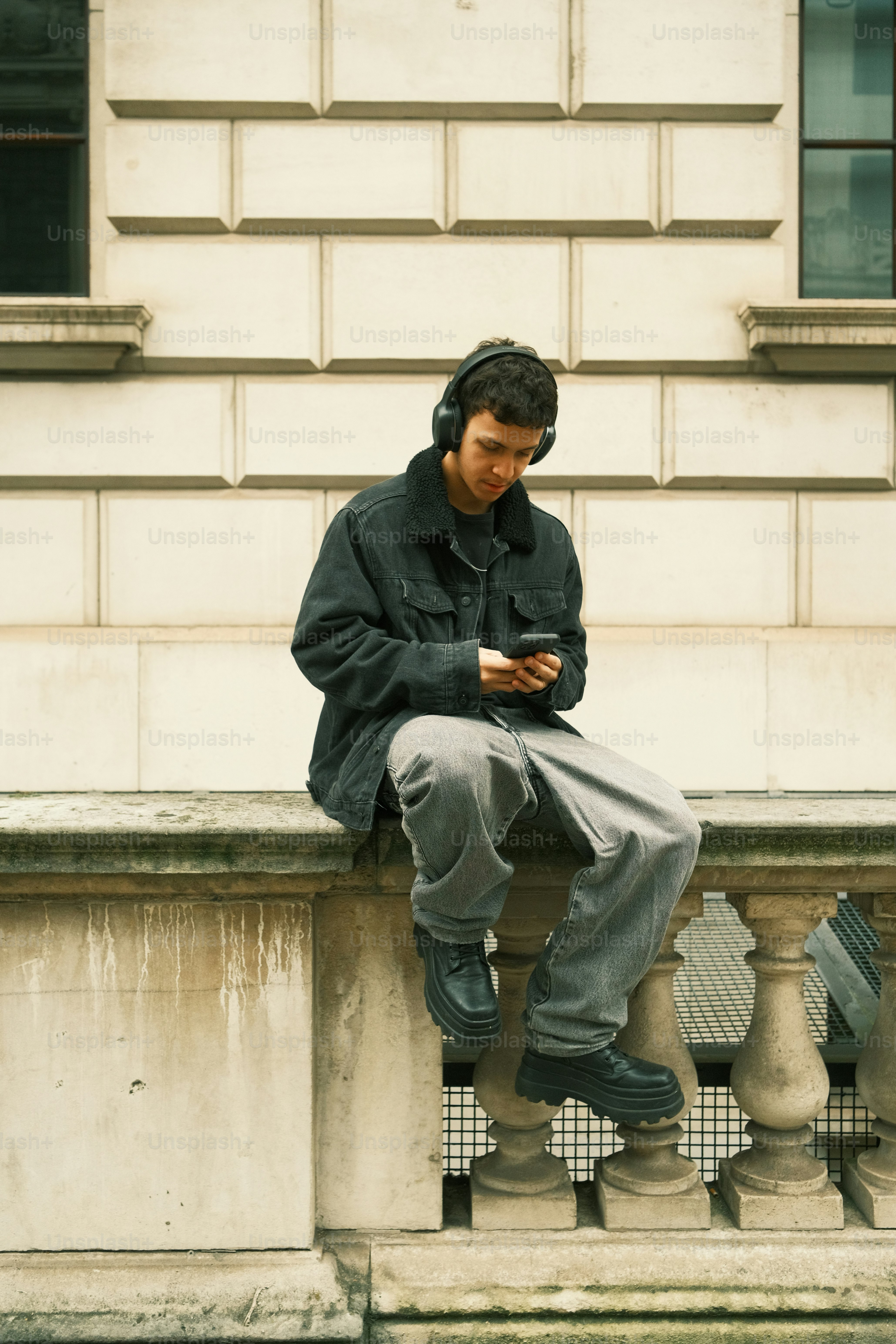 난간에 앉아 휴대폰을 보고 있는 남자