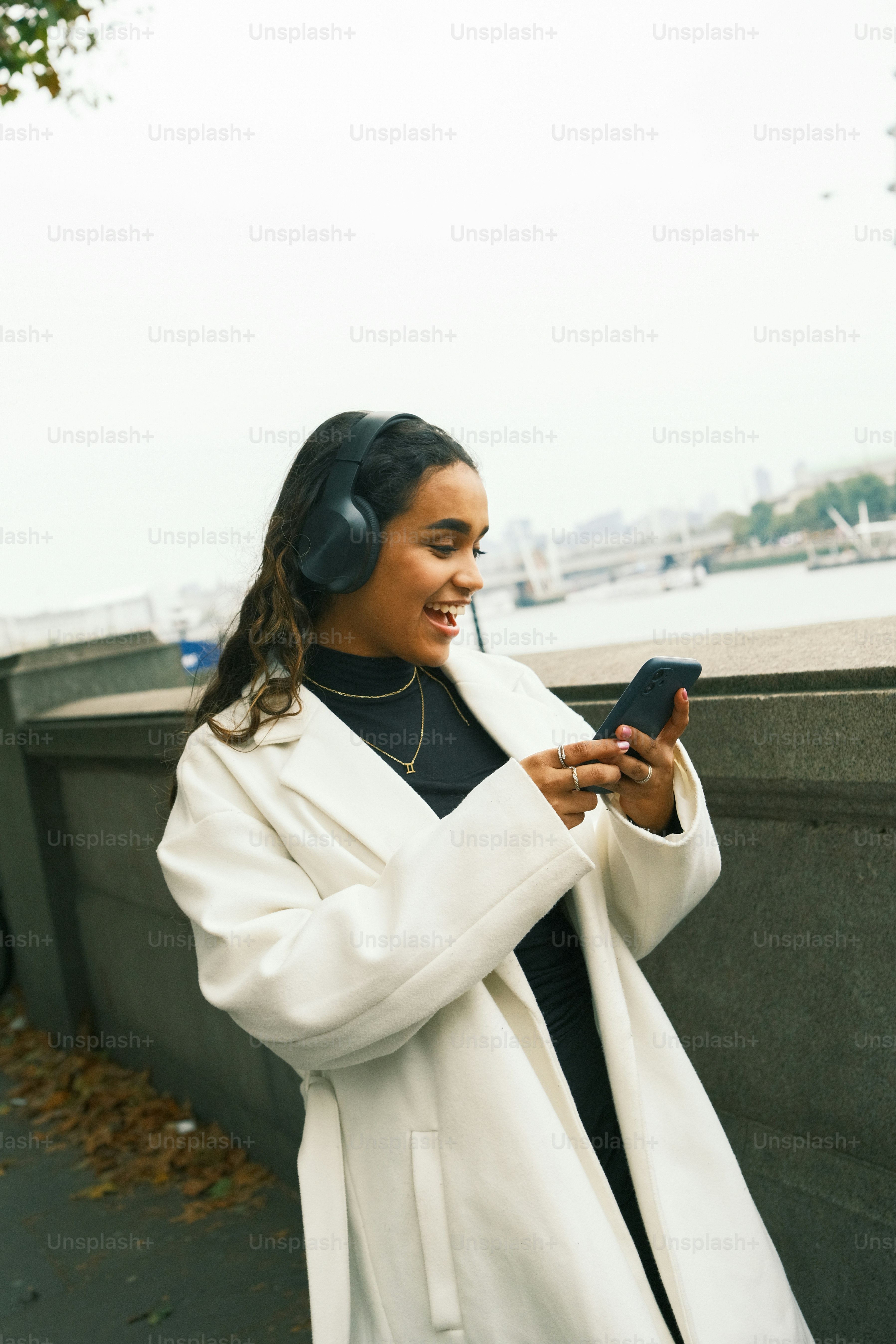 흰 코트를 입은 여성이 휴대폰을 보고 있다