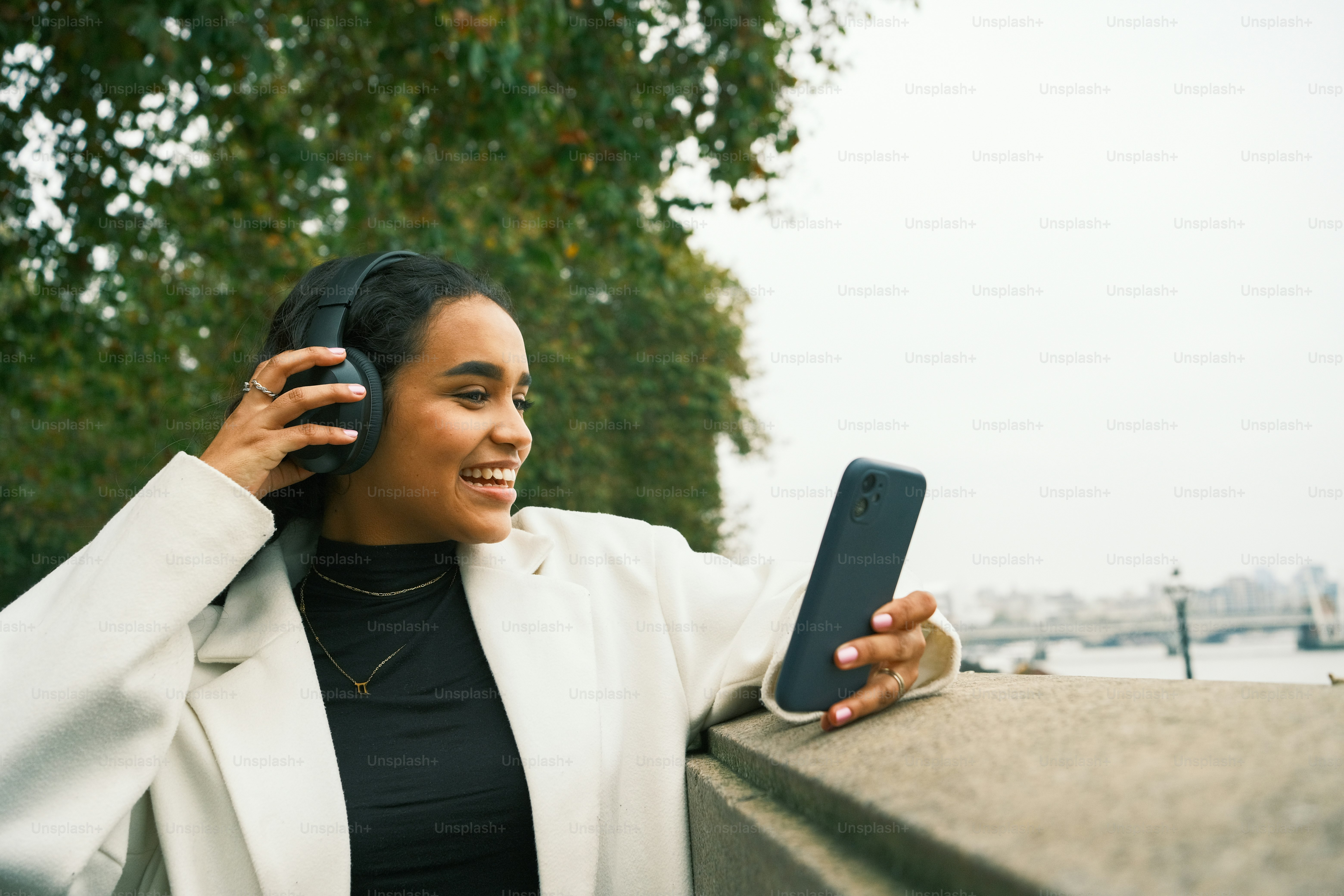 Eine Frau in einer weißen Jacke mit einem Handy in der Hand