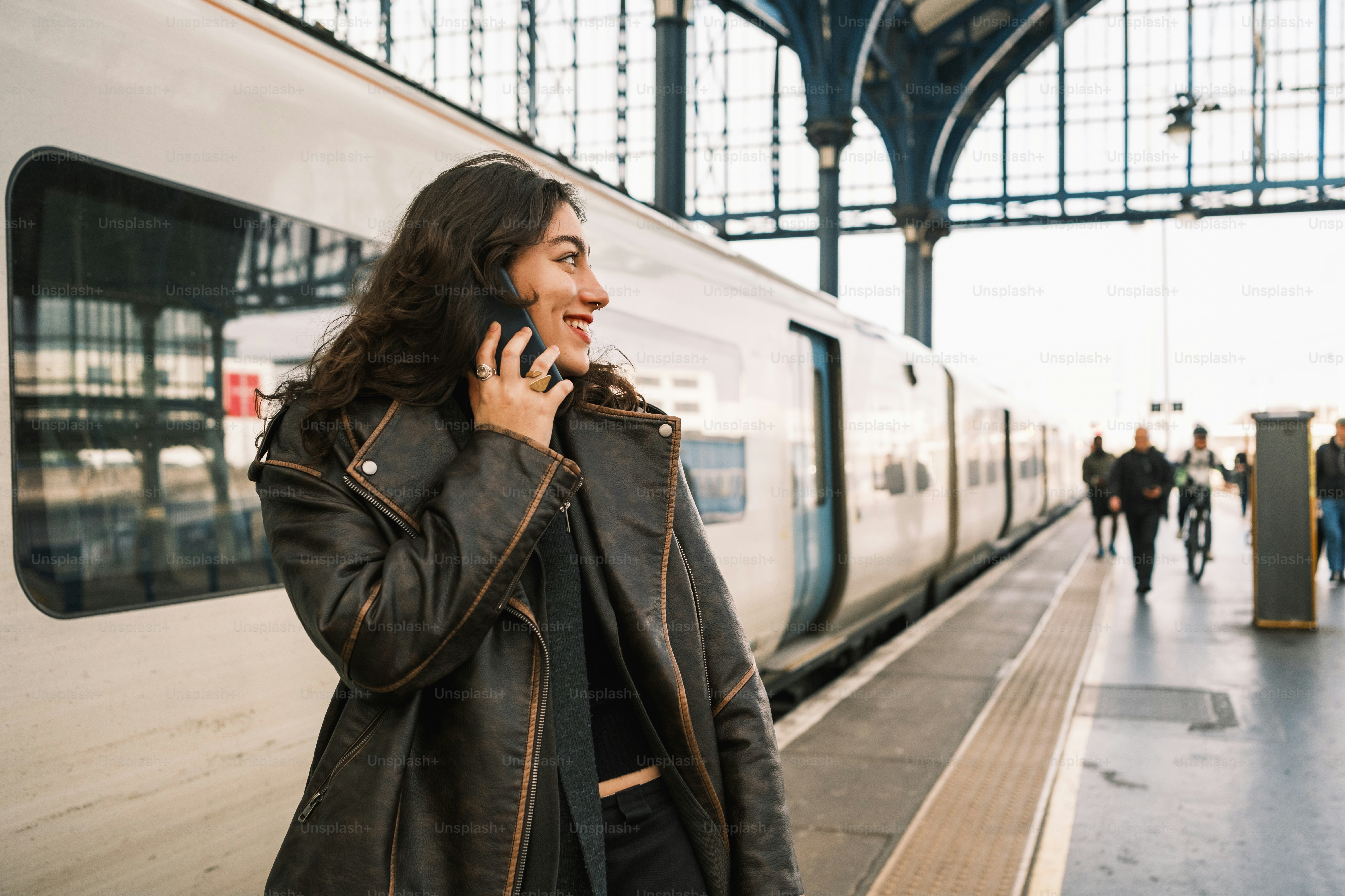 A woman talking on a cell phone next to a train