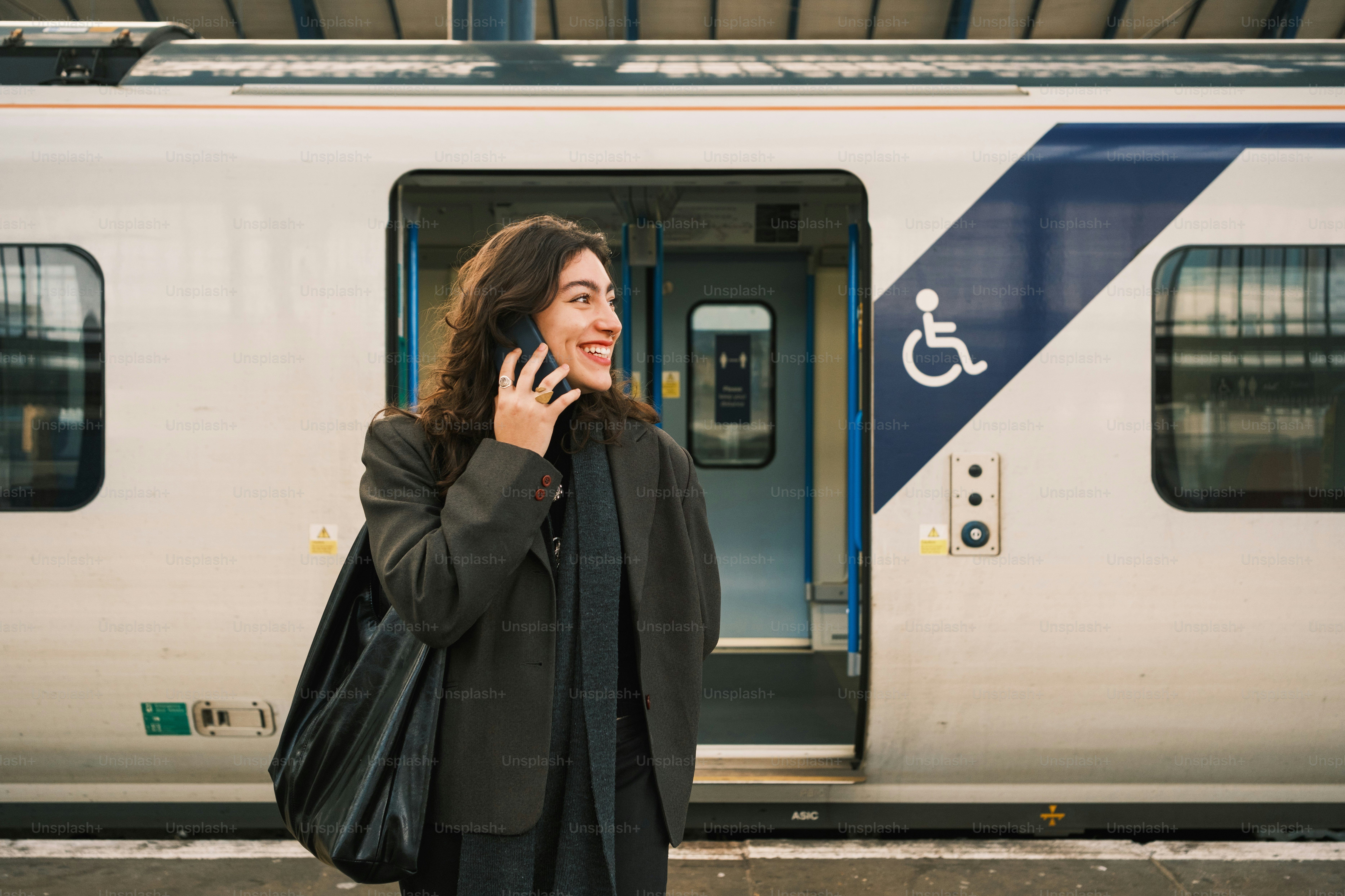 A woman talking on a cell phone next to a train