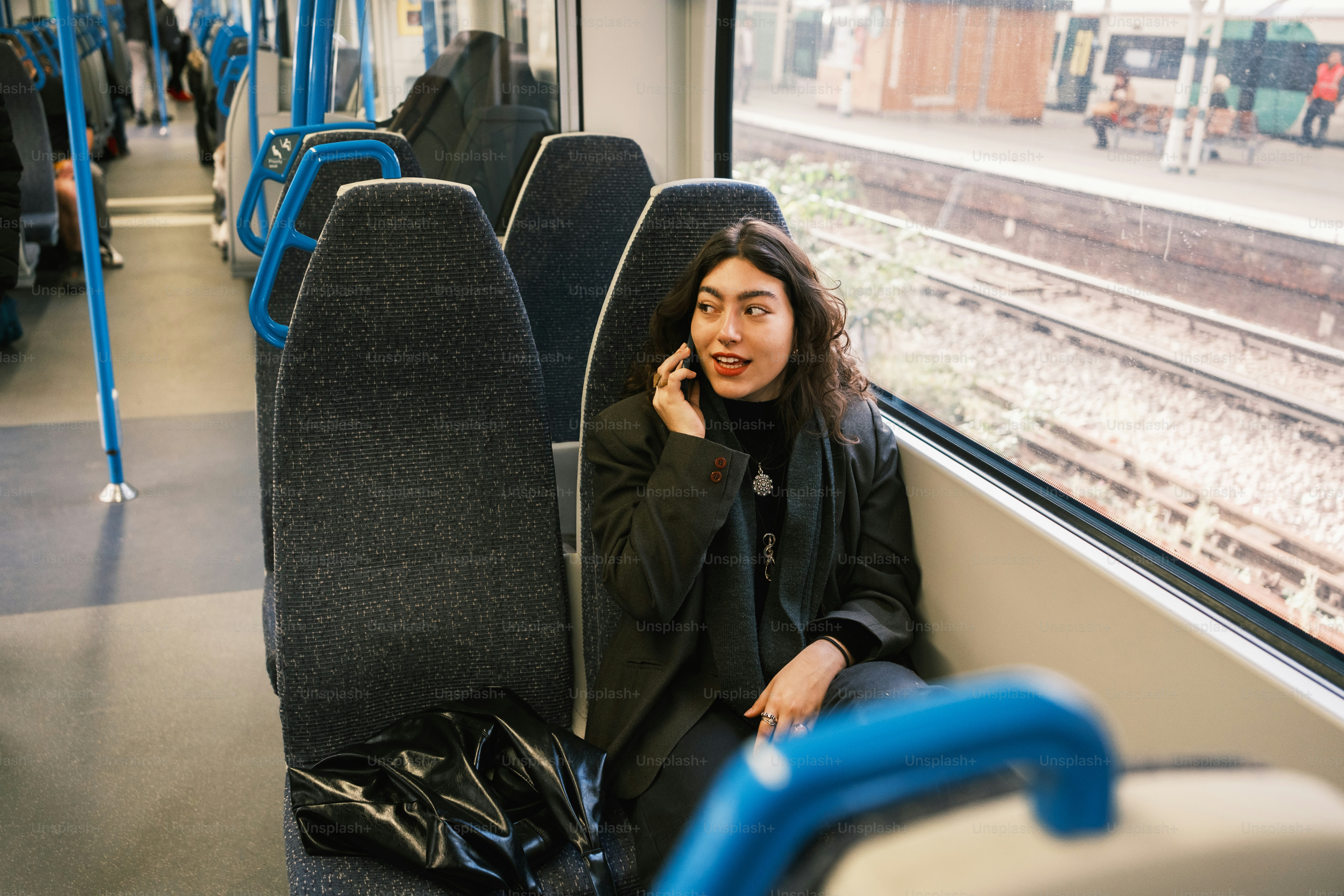 A woman sitting on a train talking on a cell phone
