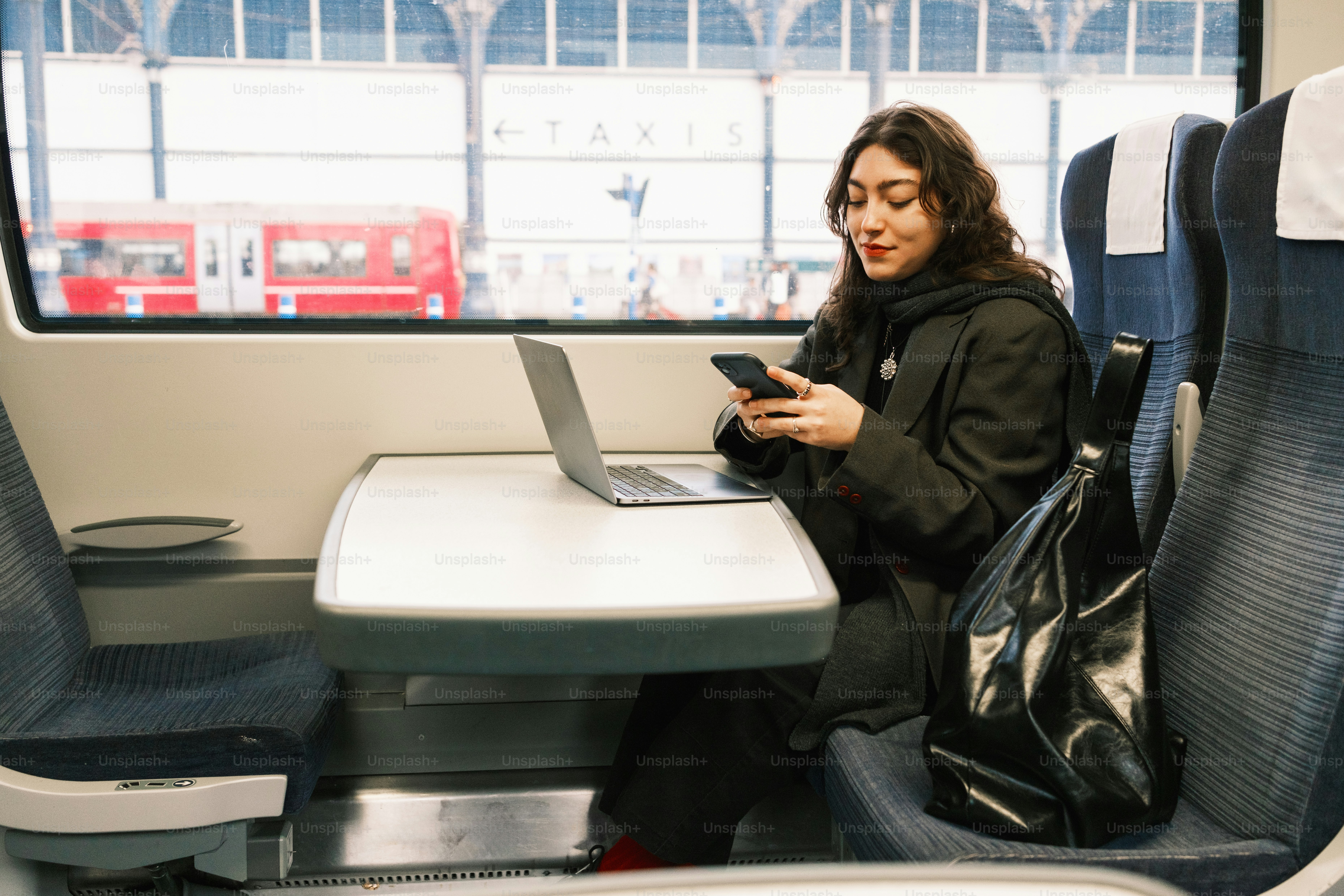 A woman sitting at a table with a laptop and a cell phone