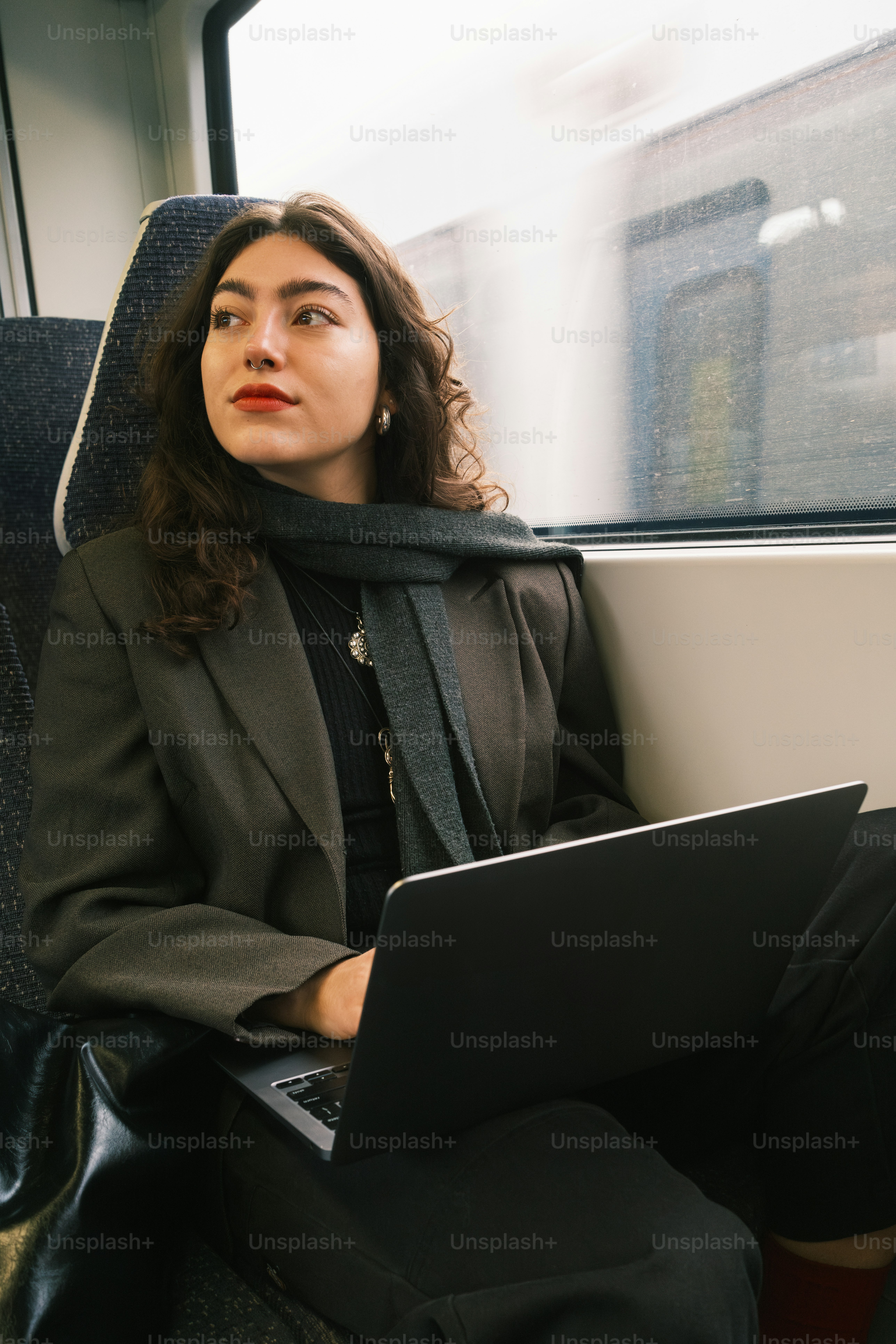 A woman sitting on a train with a laptop