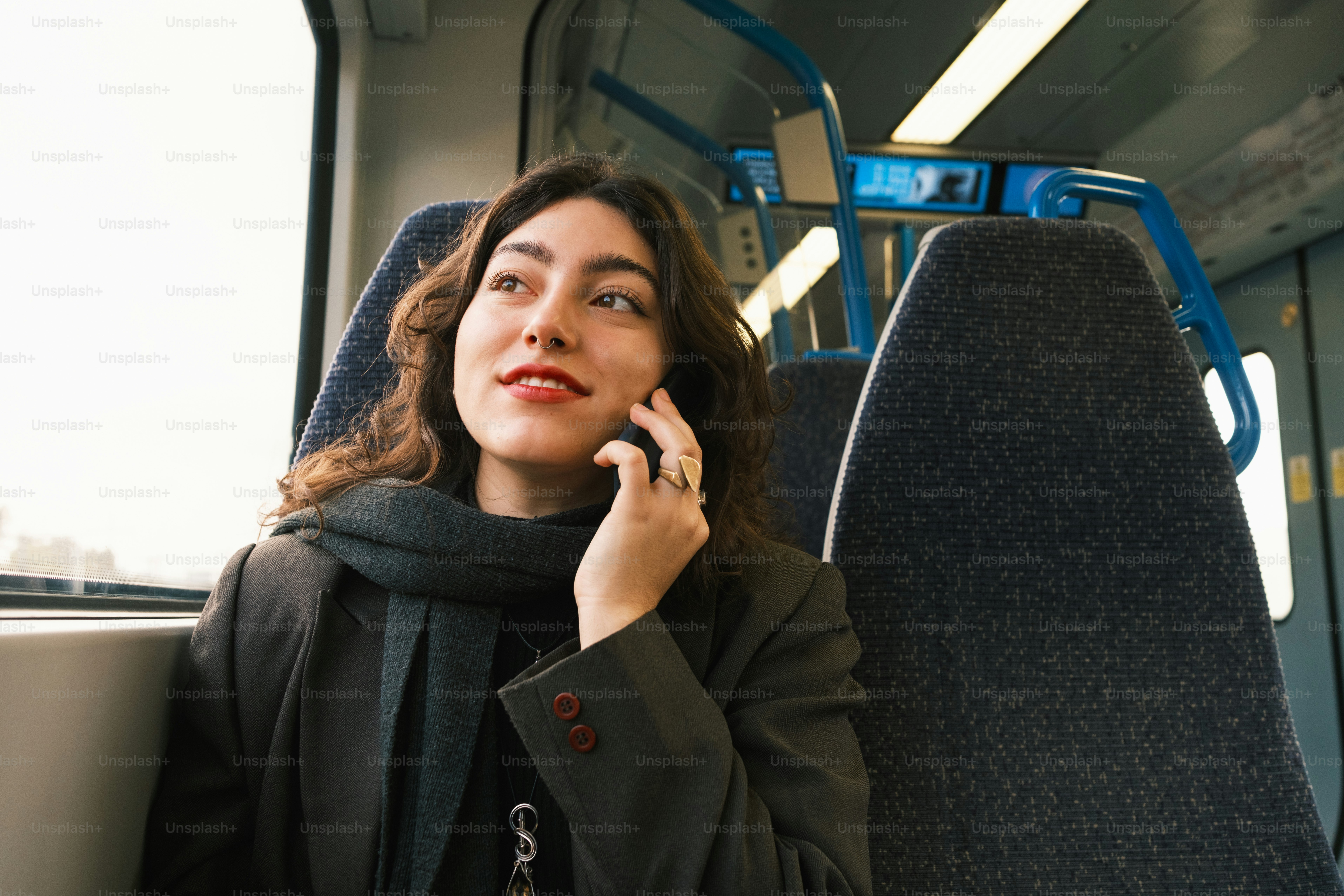A woman sitting on a bus talking on a cell phone