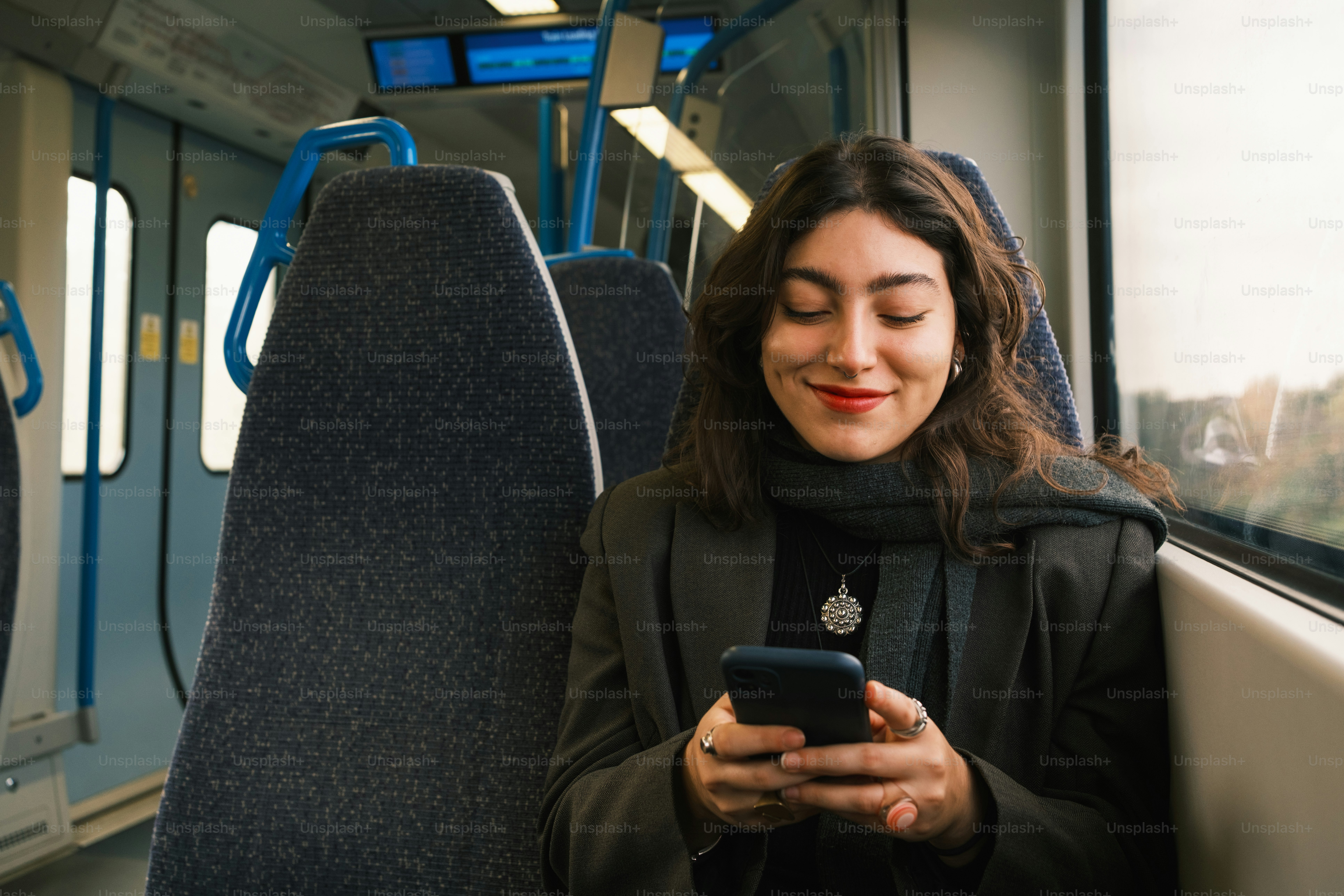 A woman sitting on a train looking at her phone