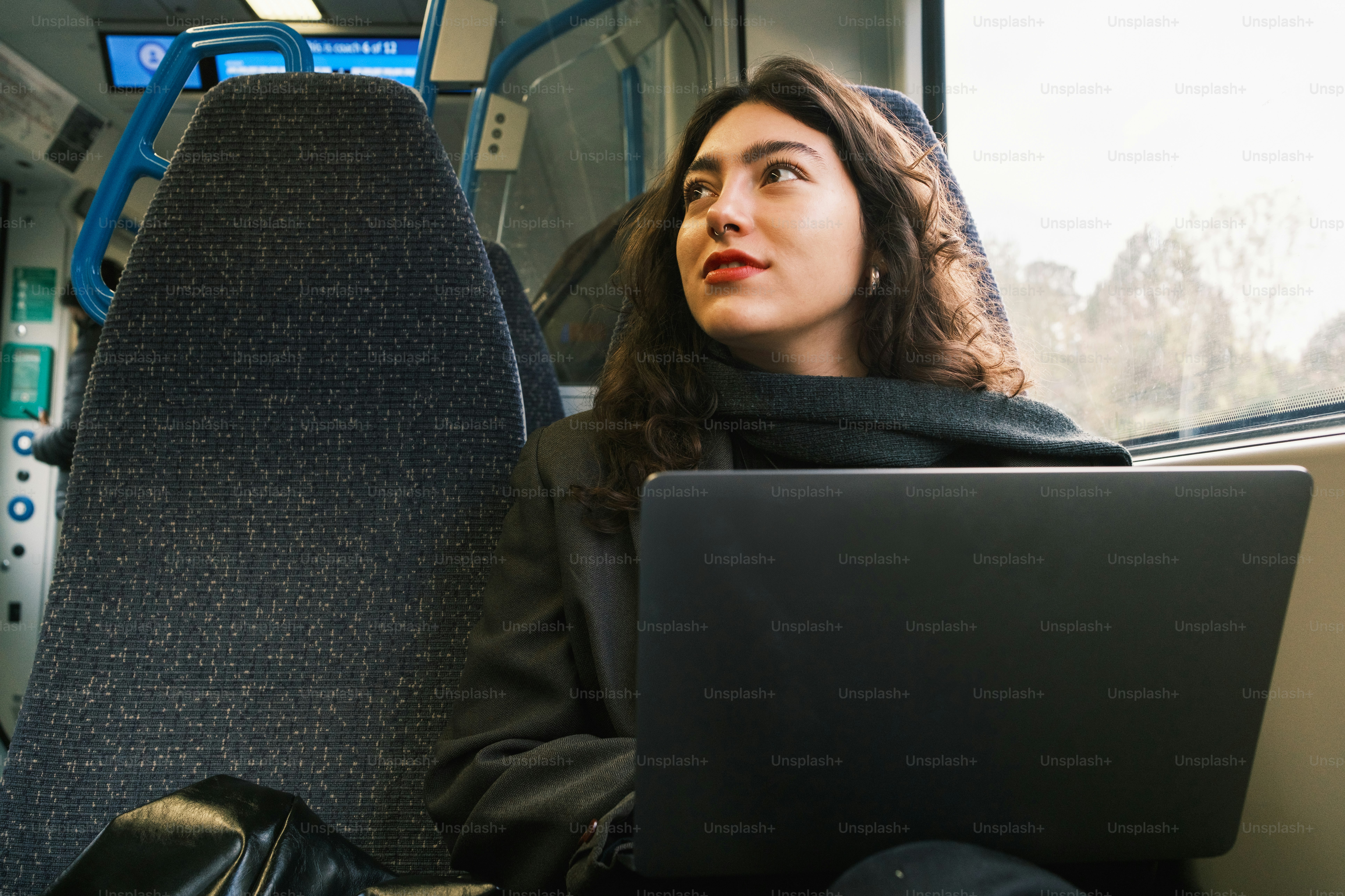 Una mujer sentada en un autobús con una computadora portátil