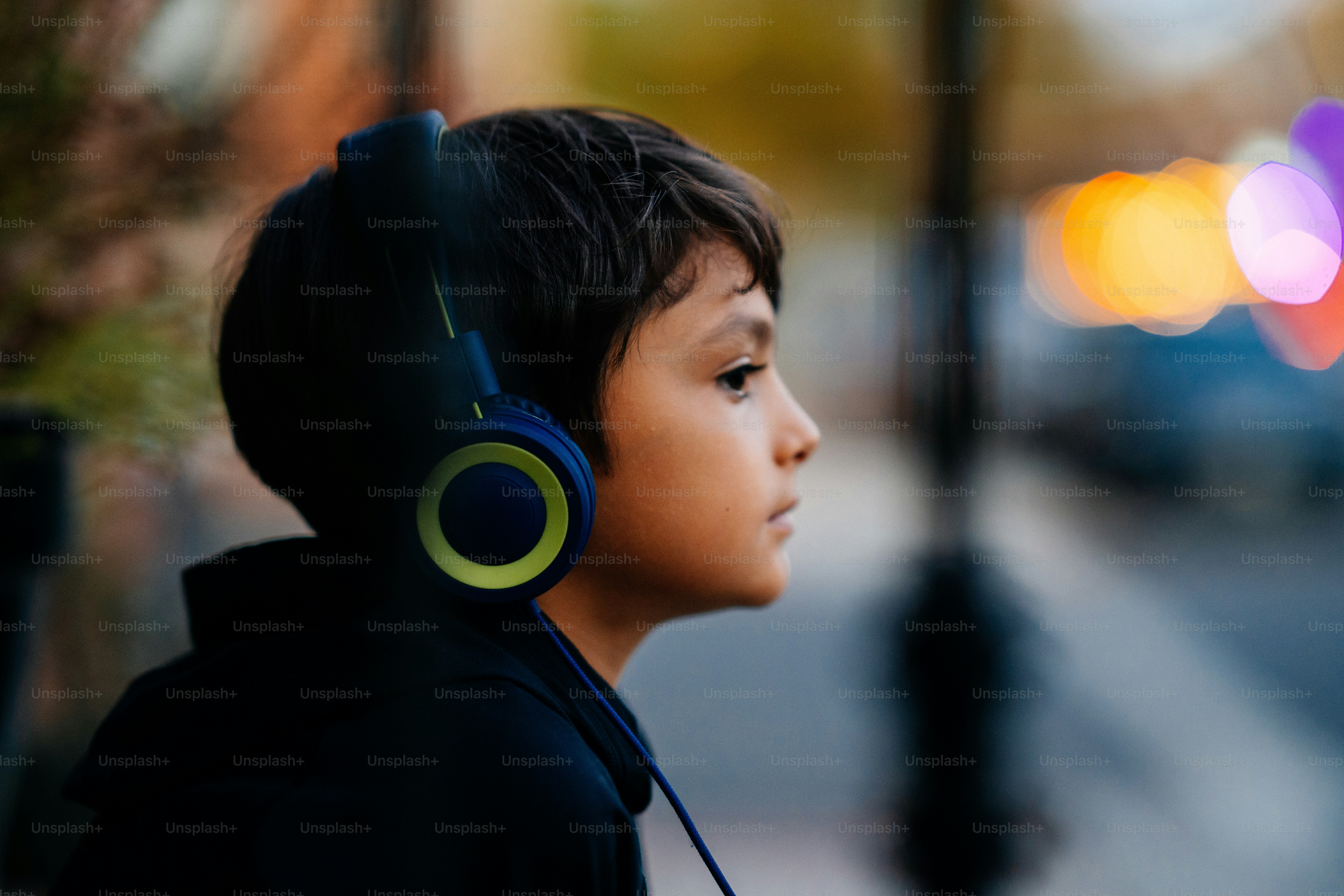 A young boy wearing headphones on a city street photo – City Image on ...