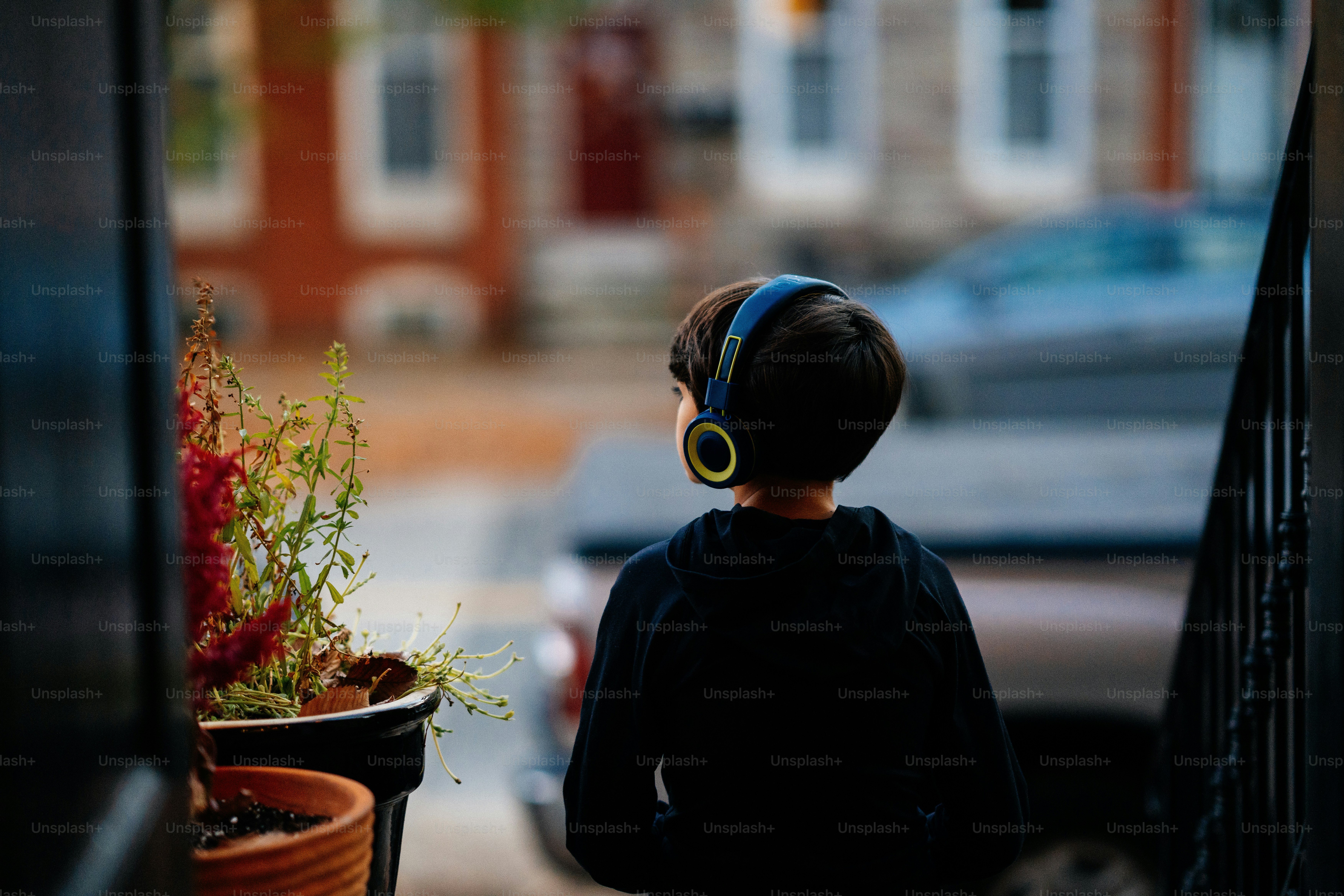 A little boy that is standing next to a potted plant