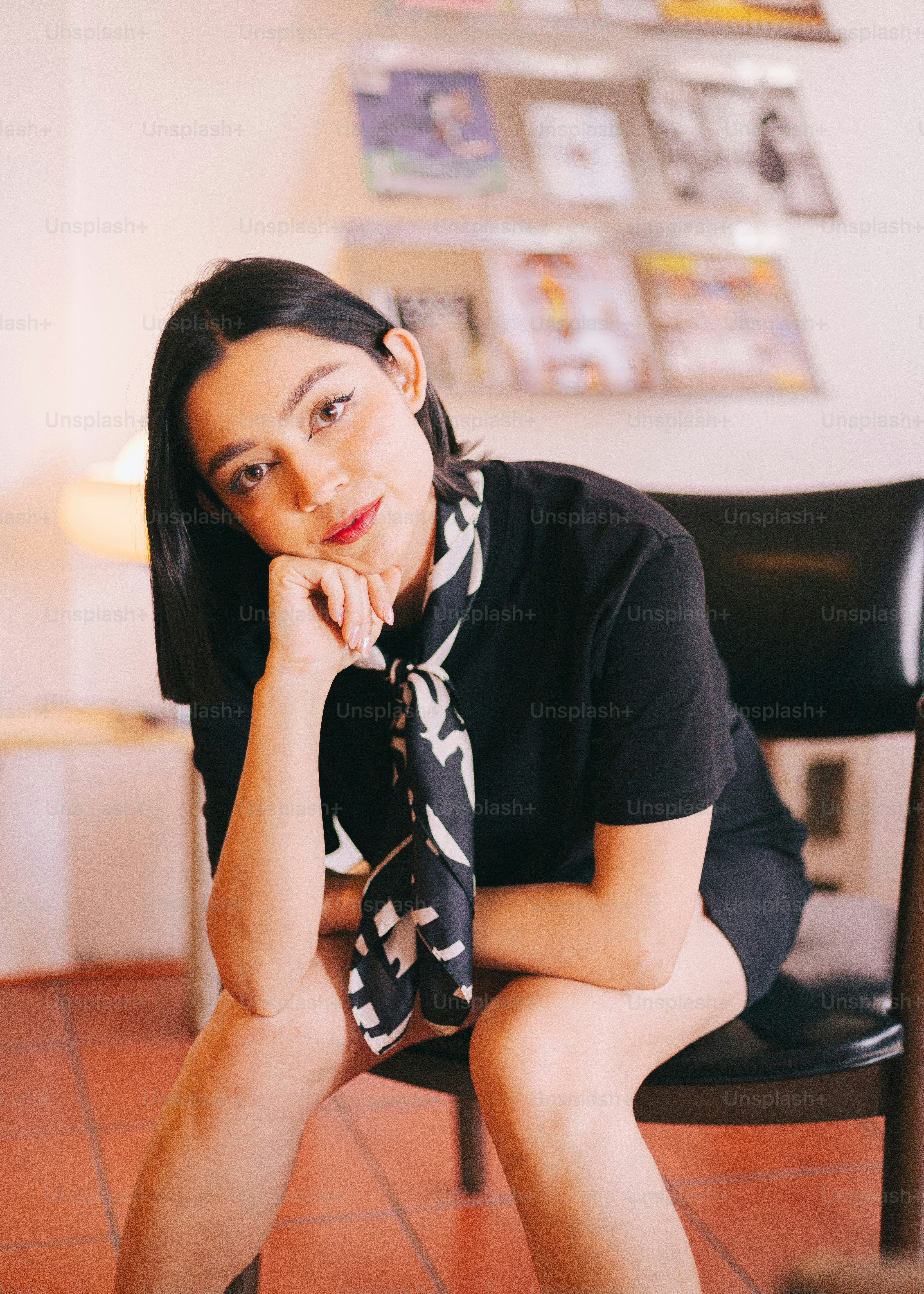 A woman sitting in a chair with her hand on her chin