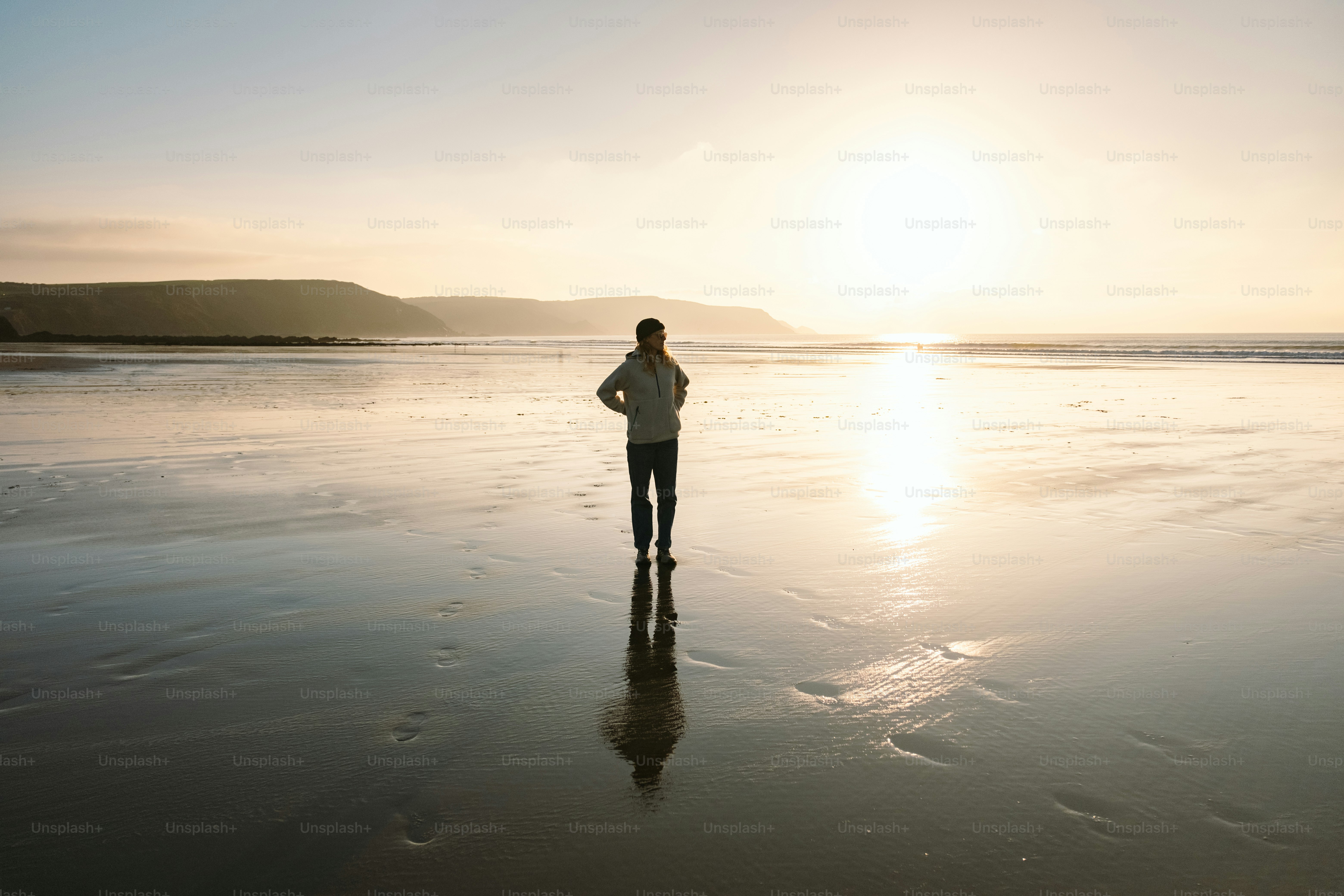 Eine Person, die bei Sonnenuntergang an einem Strand steht