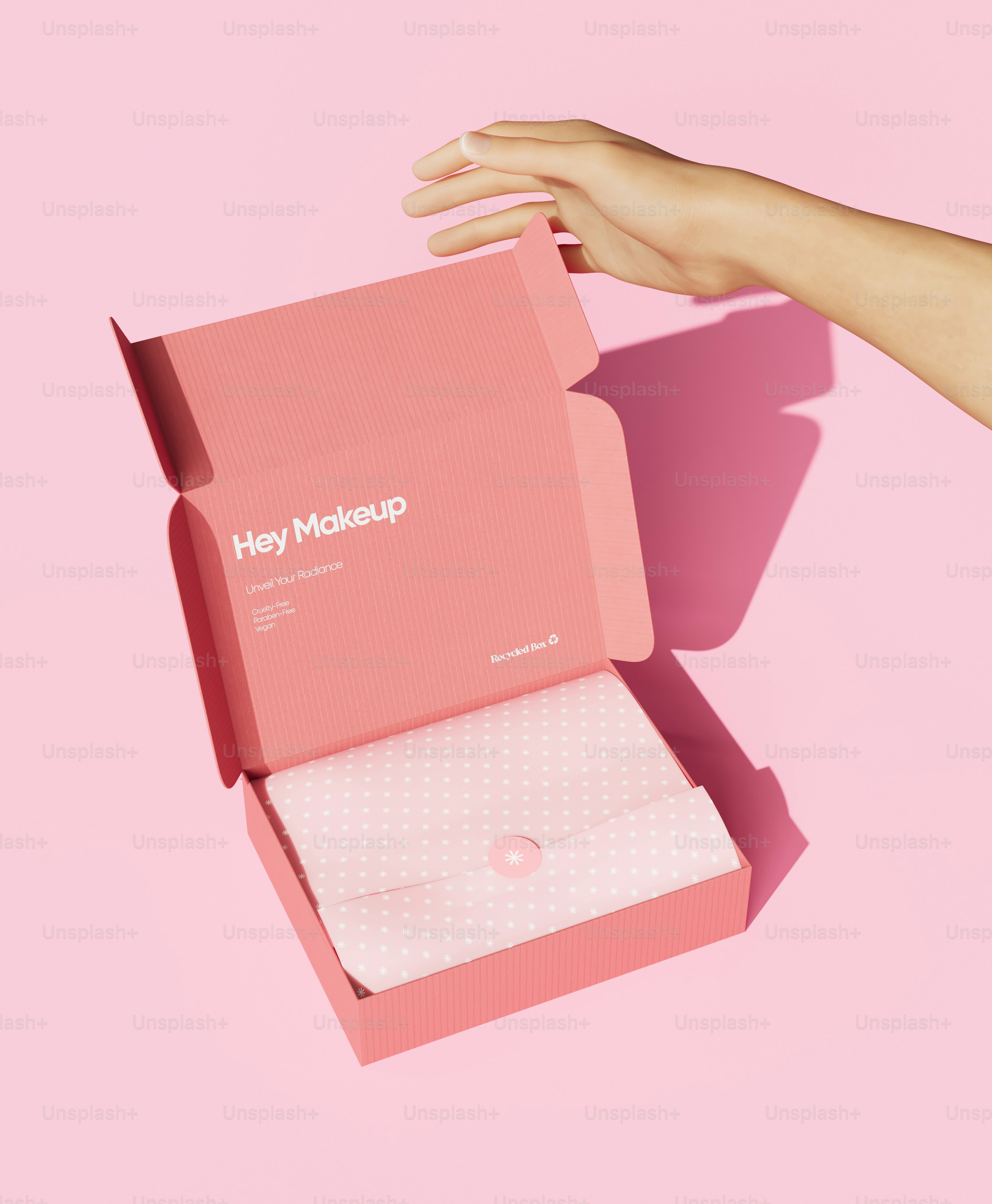 A woman's hand holding a pink box with a sheet of paper in it