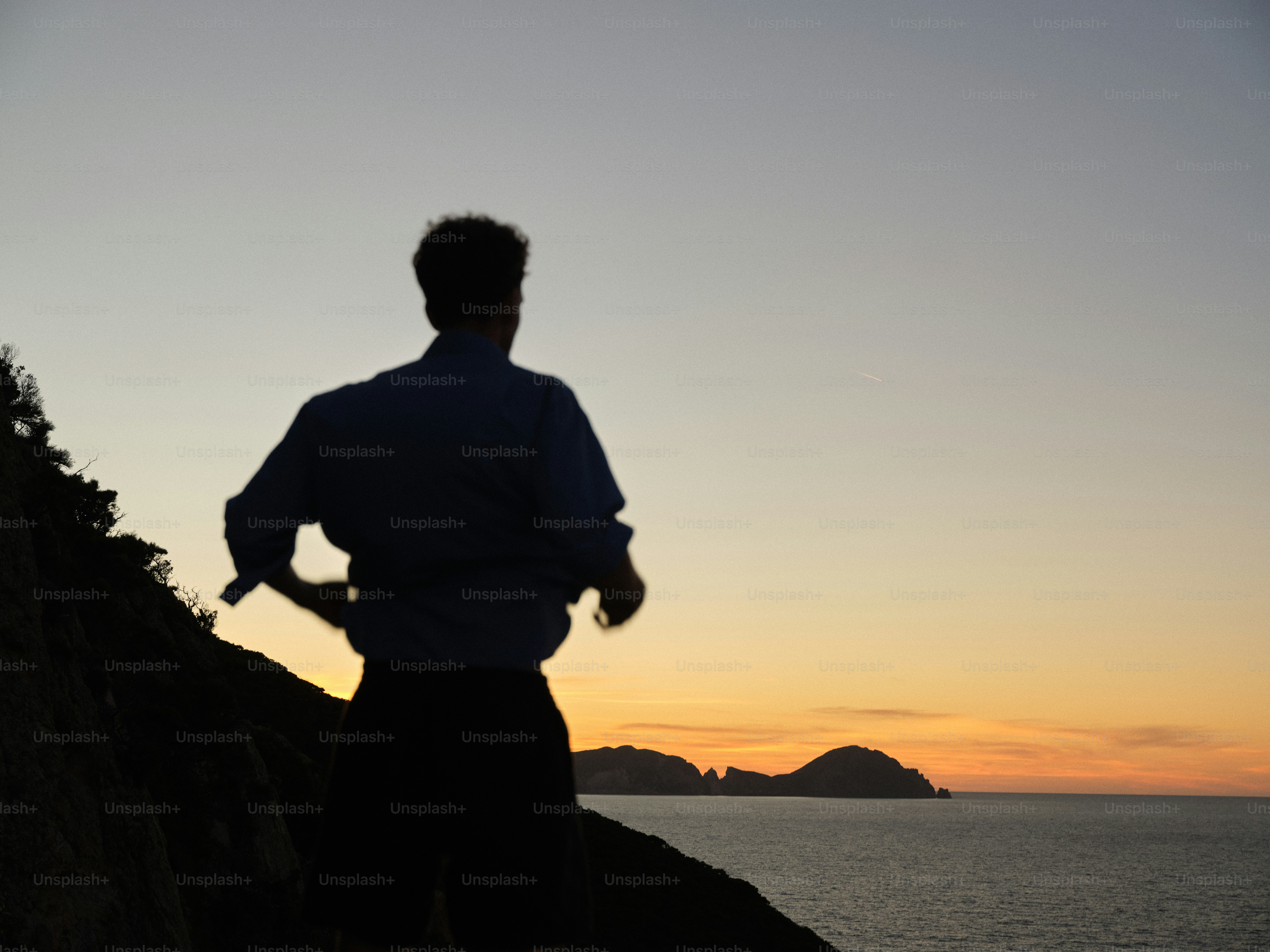 A man standing on top of a cliff next to the ocean