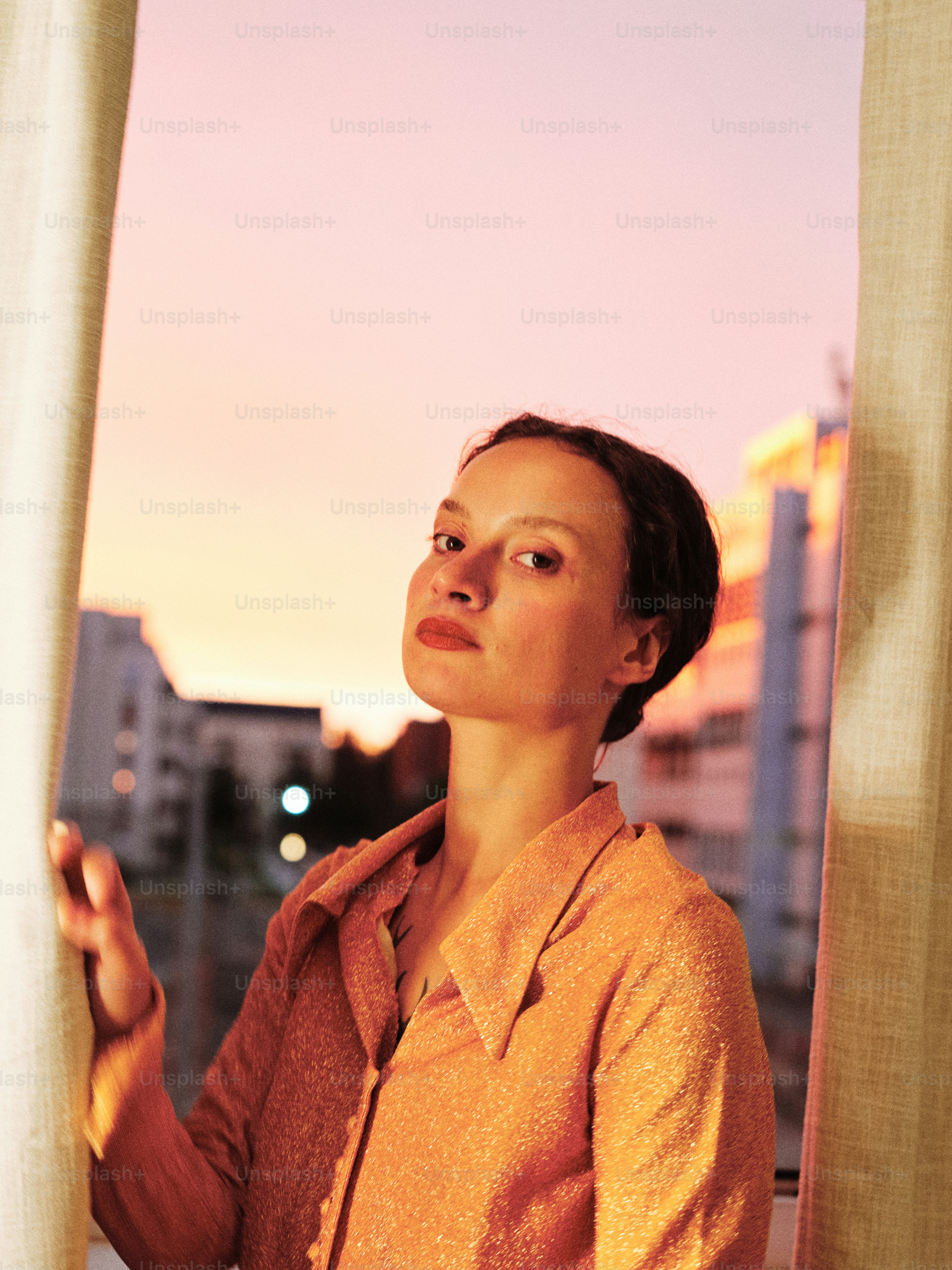 Una mujer mirando por una ventana al atardecer